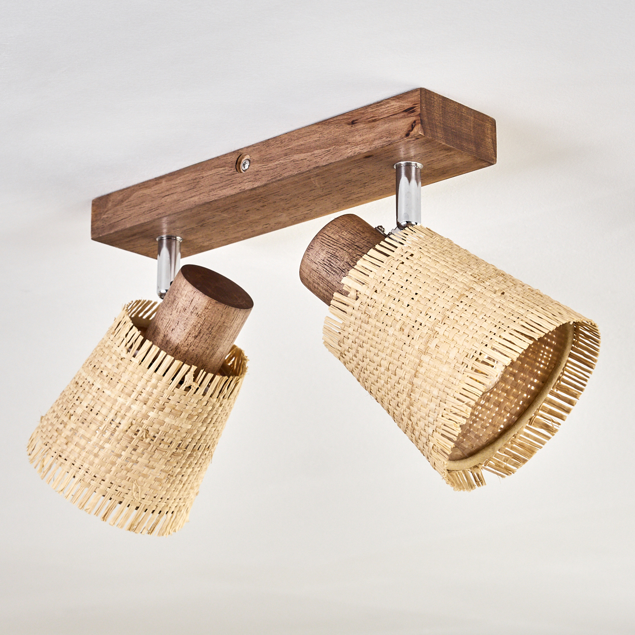 Zwei nach unten zeigende Rattanlampen, montiert an einem Holzbalken. Der Hintergrund ist weiß.