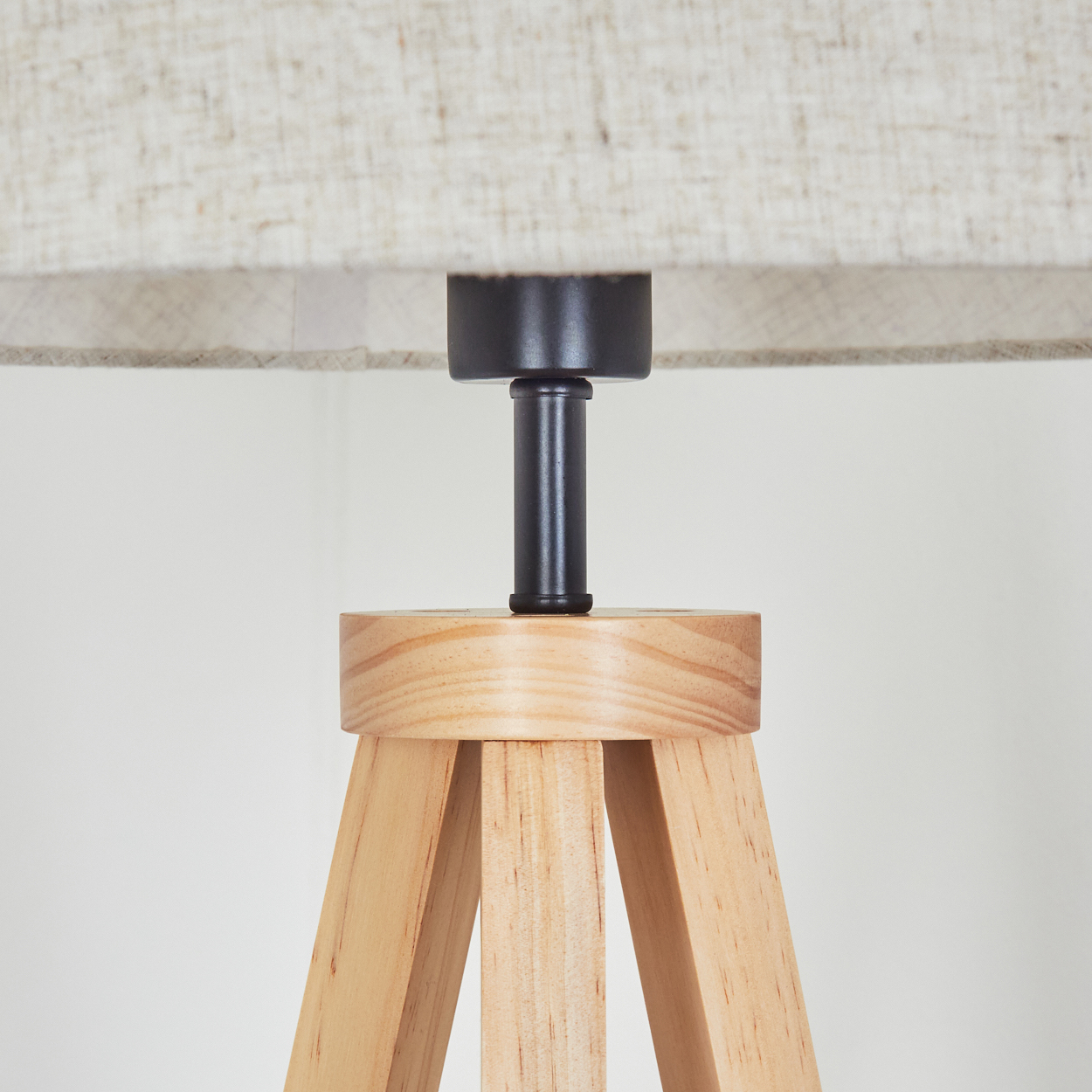 Nahaufnahme eines beigen Lampenschirms auf einem Lampensockel aus Holz. Der Hintergrund ist weiß.