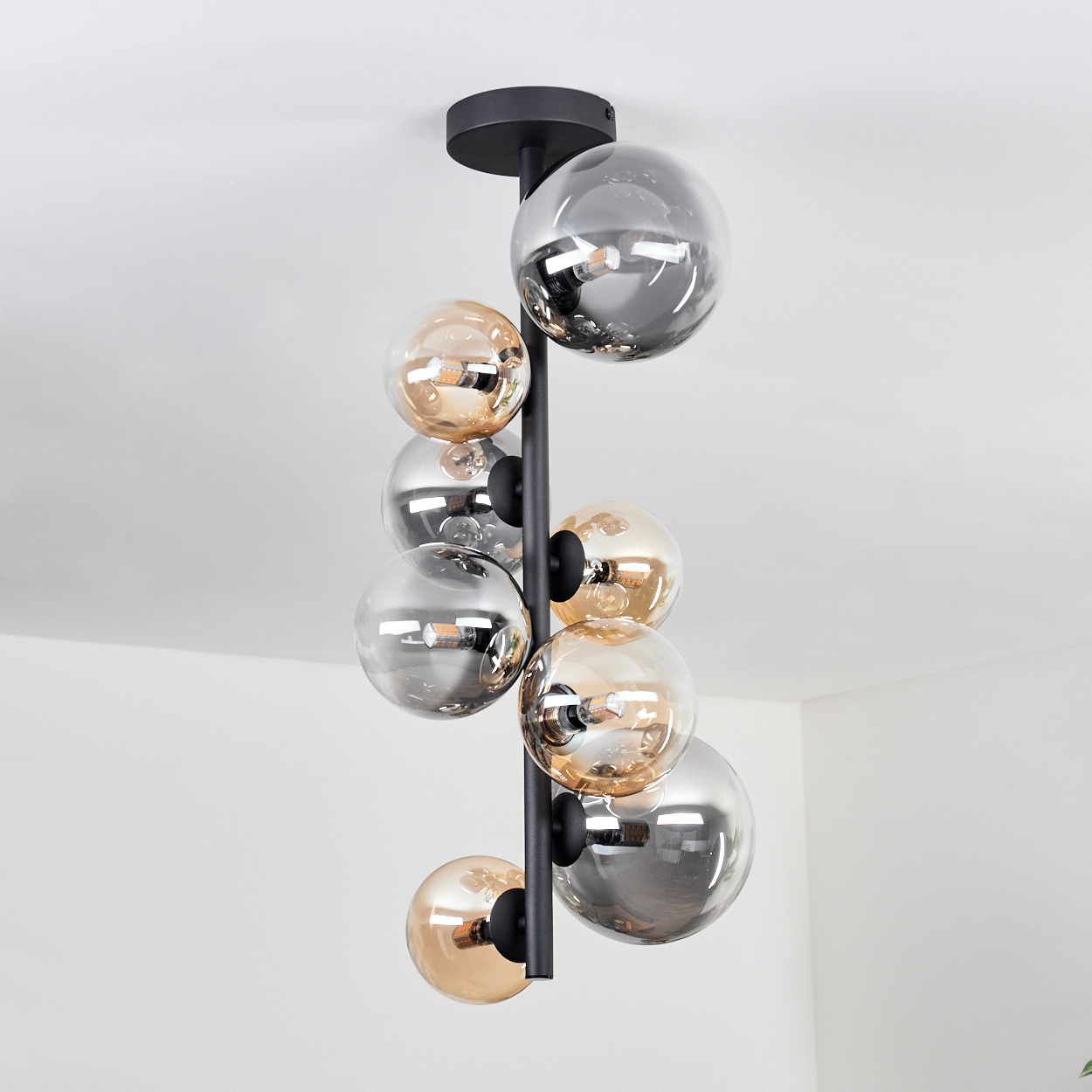 Schwarzer Kronleuchter mit Glaskugeln, gold und silber. Die Leuchte hängt von der Decke.