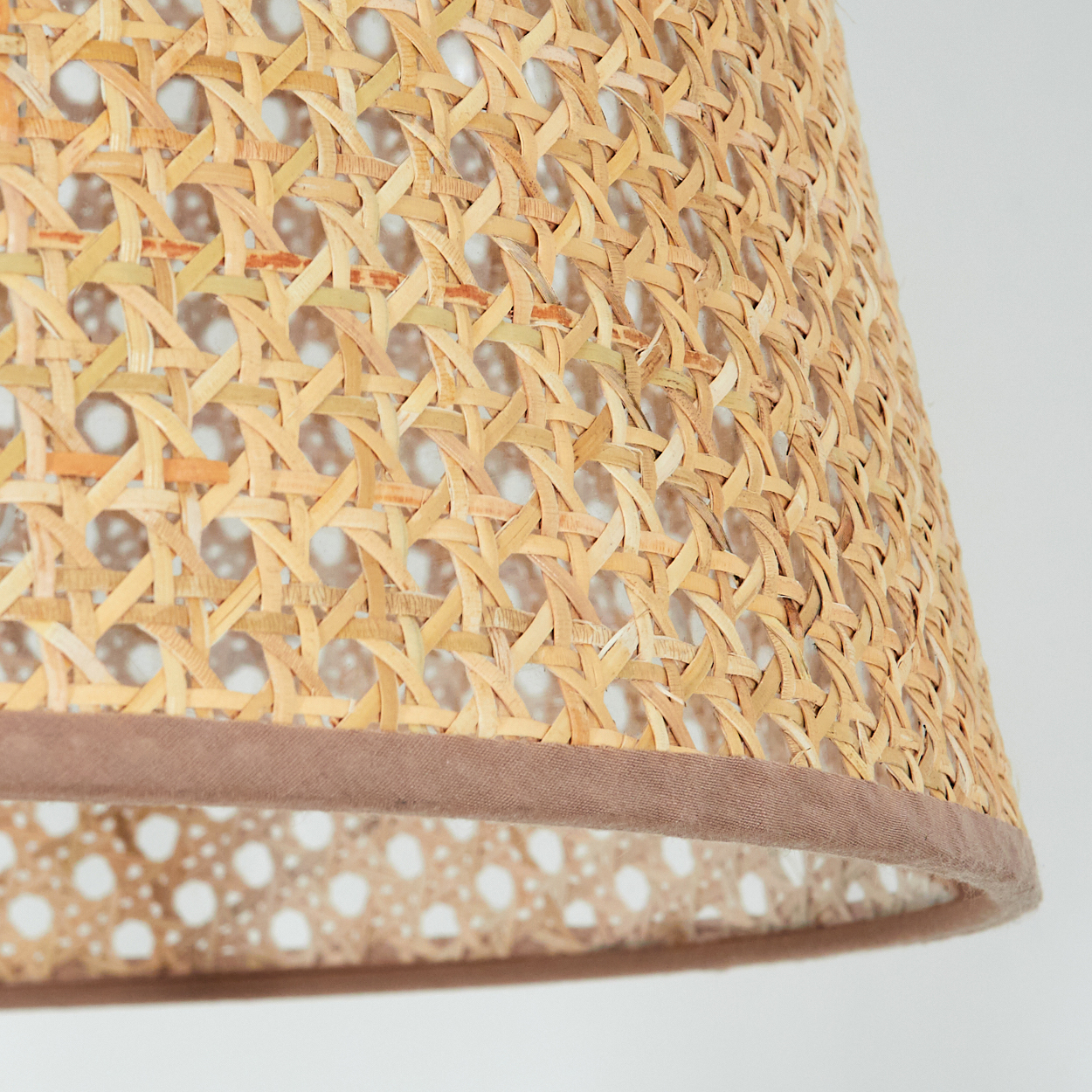 Nahaufnahme des gewebten Lampenschirmmaterials mit braunem Rand. Detailliertes Muster.