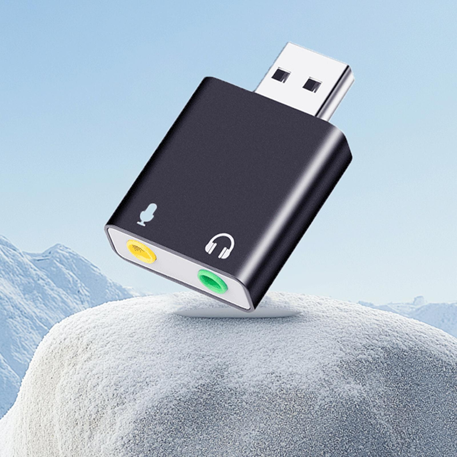 Ein schwarzer USB-Audioadapter mit Mikrofon- und Kopfhöreranschluss, der auf einer schneebedeckten Oberfläche liegt.