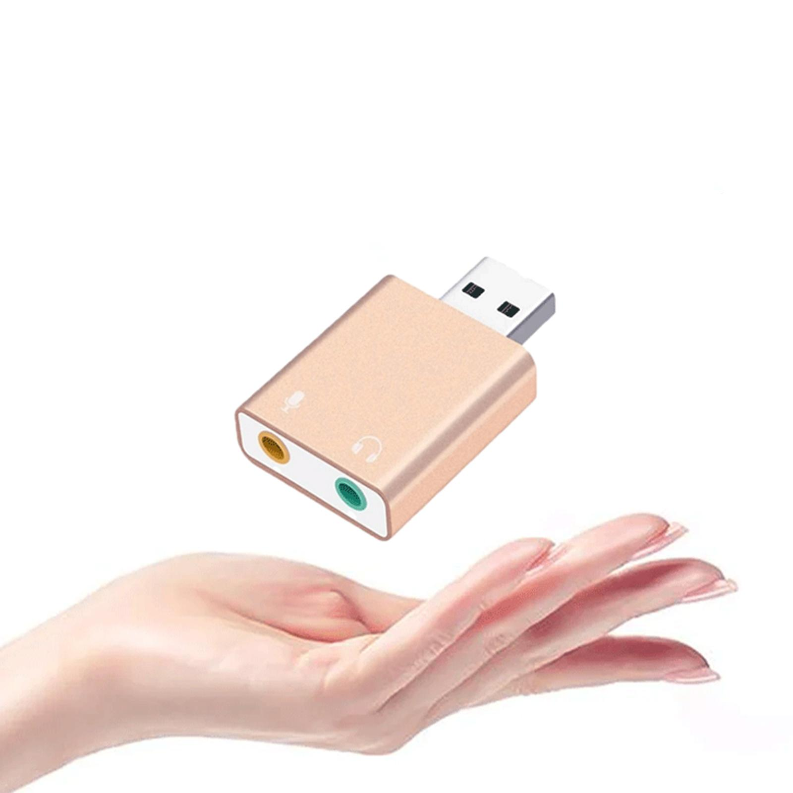 Hand hält goldenen USB-Audioadapter mit Mikrofon- und Kopfhöreranschlüssen. Weißer Hintergrund.