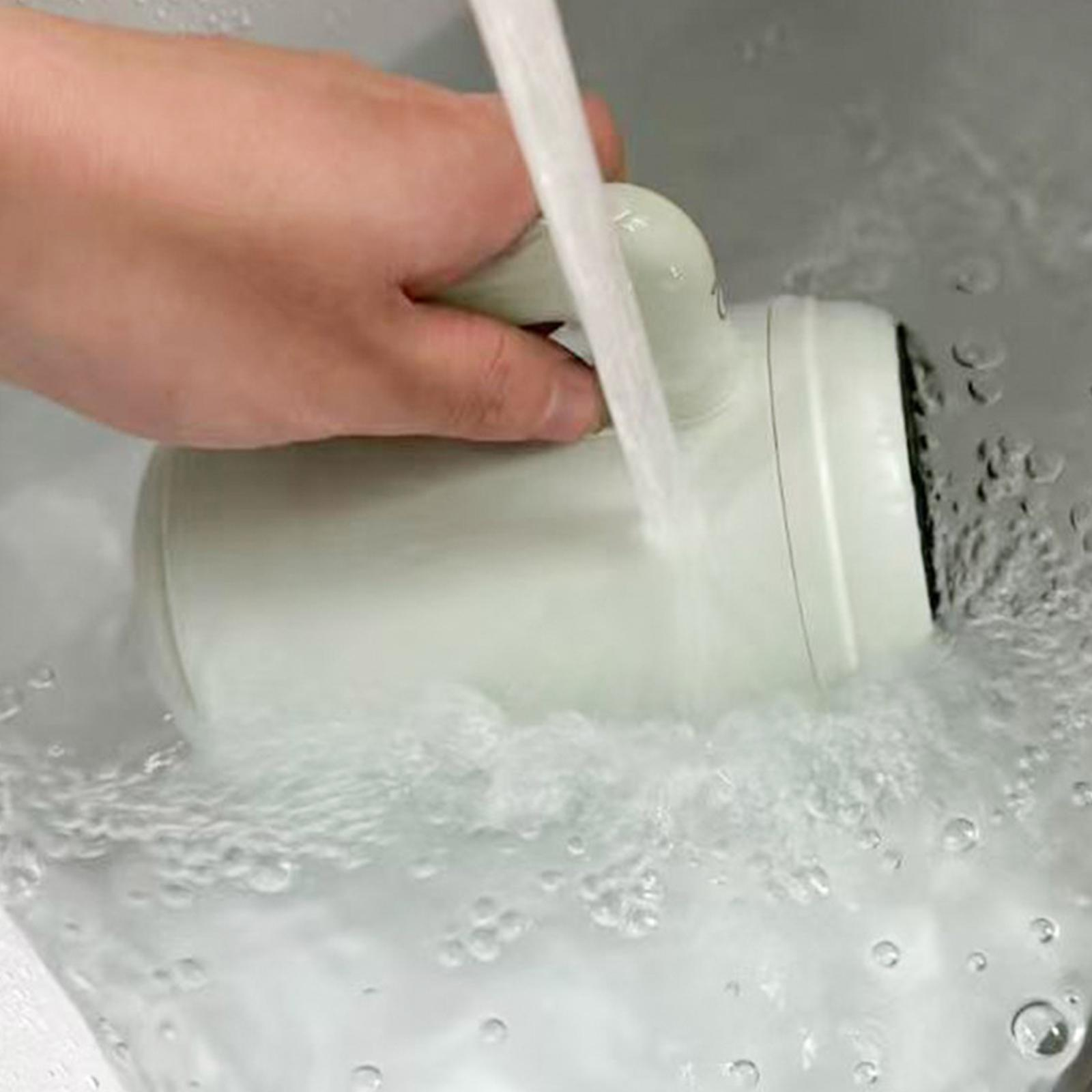 Eine Hand hält einen grünen Becher unter fließendes Wasser. Wasser spritzt. Die Szene ist in einem weißen Waschbecken.