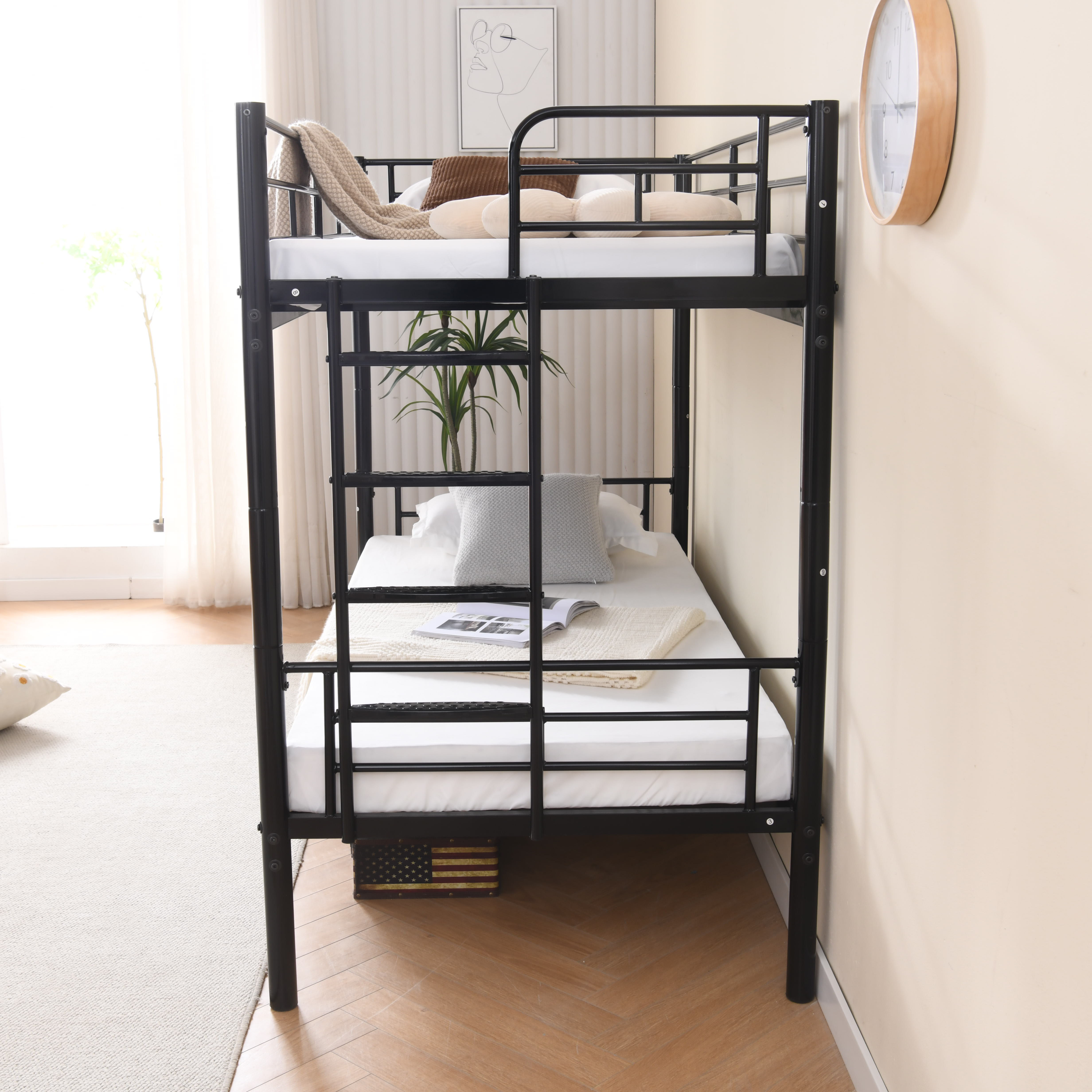 Ein schwarzes Metall-Etagenbett. Es hat zwei Ebenen mit Matratzen. Der Rahmen ist sichtbar.