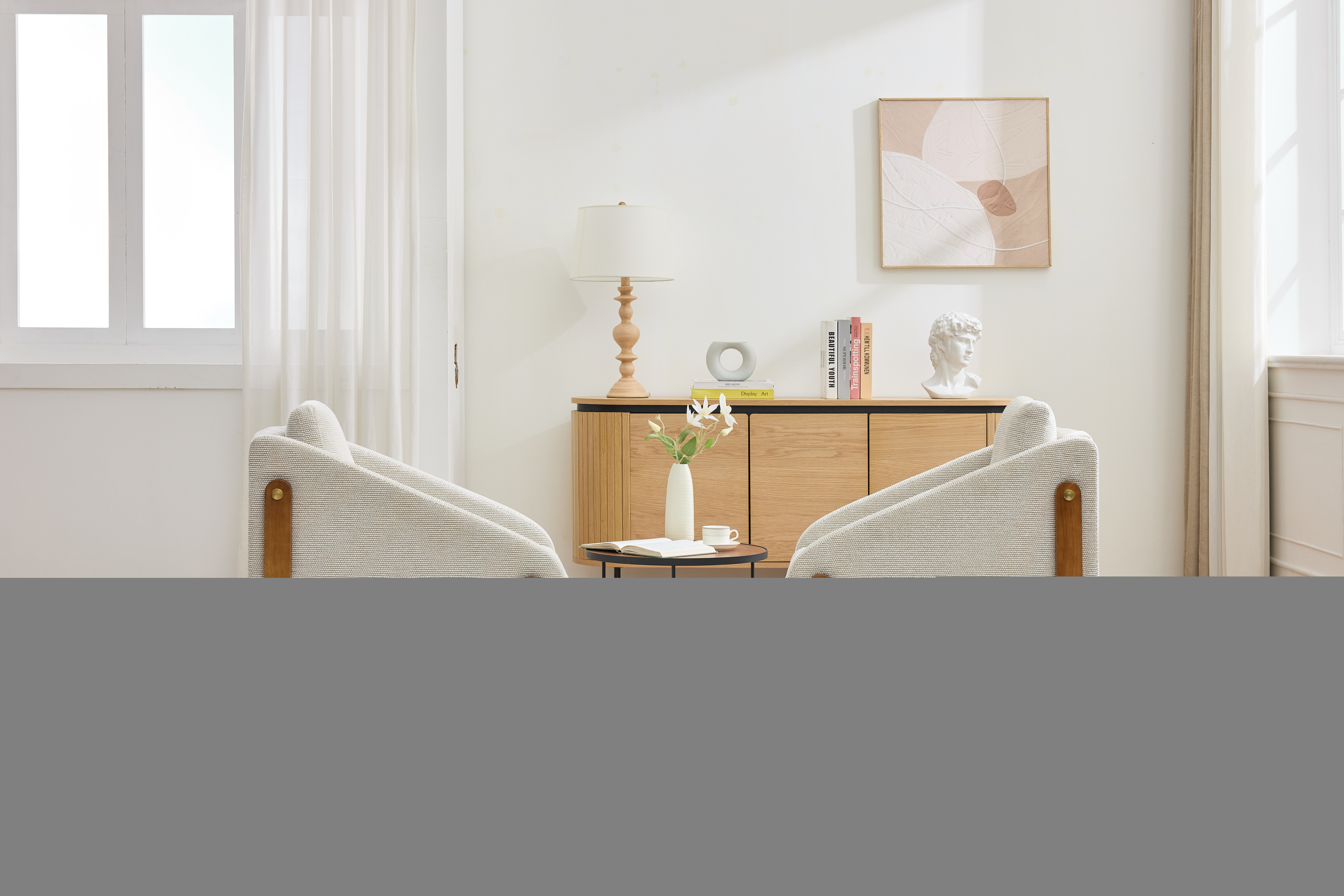 Zwei Sessel in einem hellen Raum. Ein Schrank, eine Lampe und Kunstwerke sind im Hintergrund zu sehen.