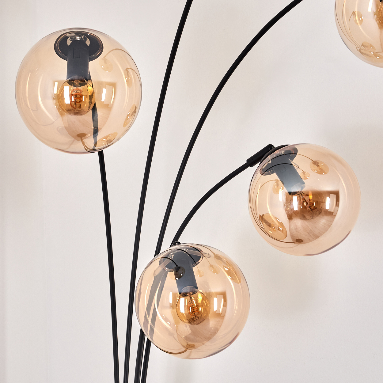 Nahaufnahme einer Stehlampe mit vier goldenen Kugeln. Jede Kugel hat eine Glühbirne und einen schwarzen Stiel.