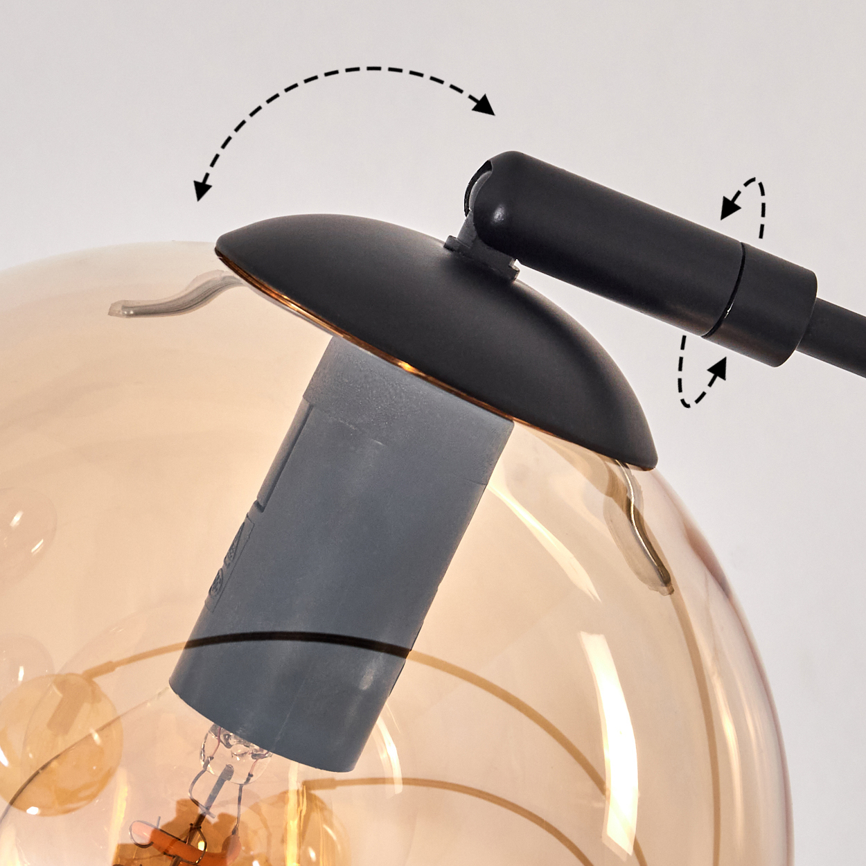 Nahaufnahme eines Lampenkopfes mit einem goldenen Globus. Zeigt, wie der Globus mit einem schwarzen Griff eingestellt wird.