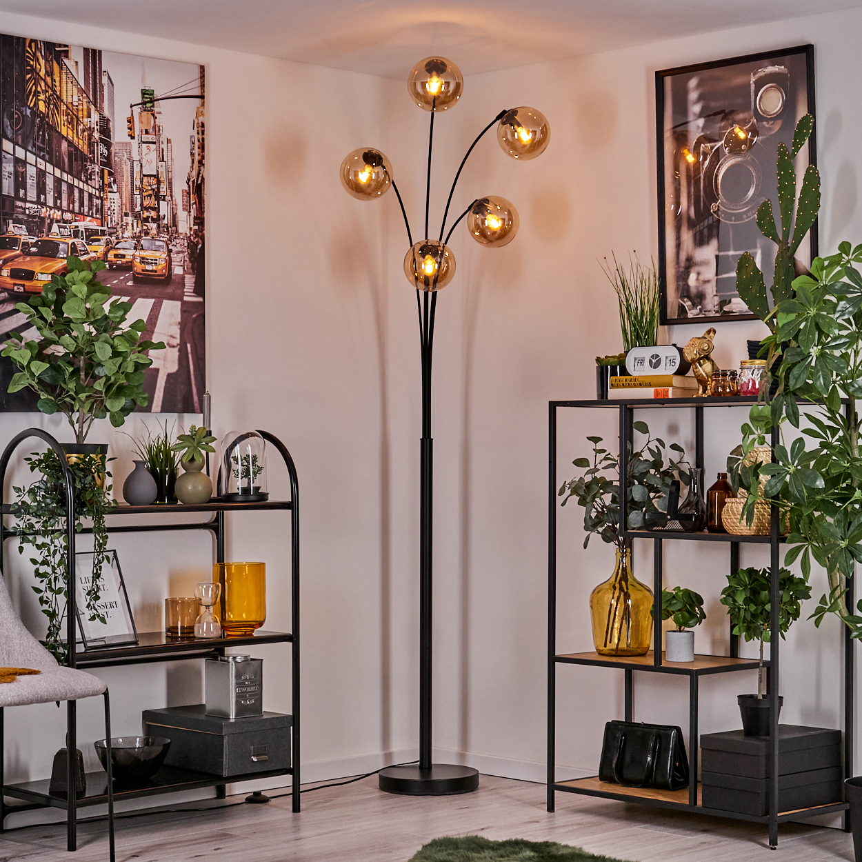 Zimmer mit Stehlampe, Regalen und Dekoration. Die Stehlampe hat fünf goldene Kugeln. Enthält Pflanzen und ein gerahmtes Bild.