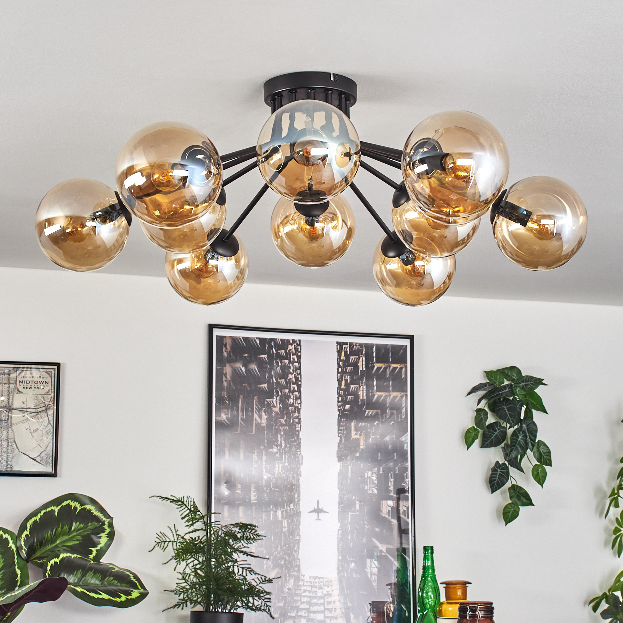 Eine Deckenleuchte mit mehreren Kugelleuchten, mit Pflanzen und einem Bild an der Wand.