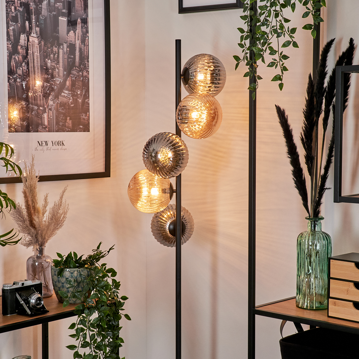 Stehlampe mit vier Glaskugeln, New York Poster, Pflanzen und einem Holzregal.