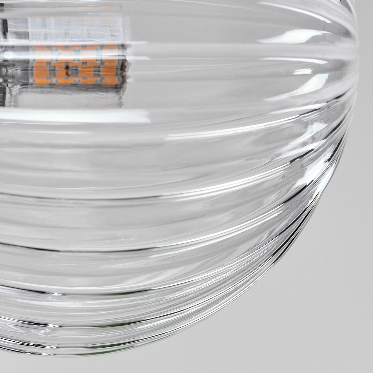 Nahaufnahme eines klaren Glasglobus mit geriffelter Textur. Eine LED-Glühbirne ist im Inneren sichtbar.