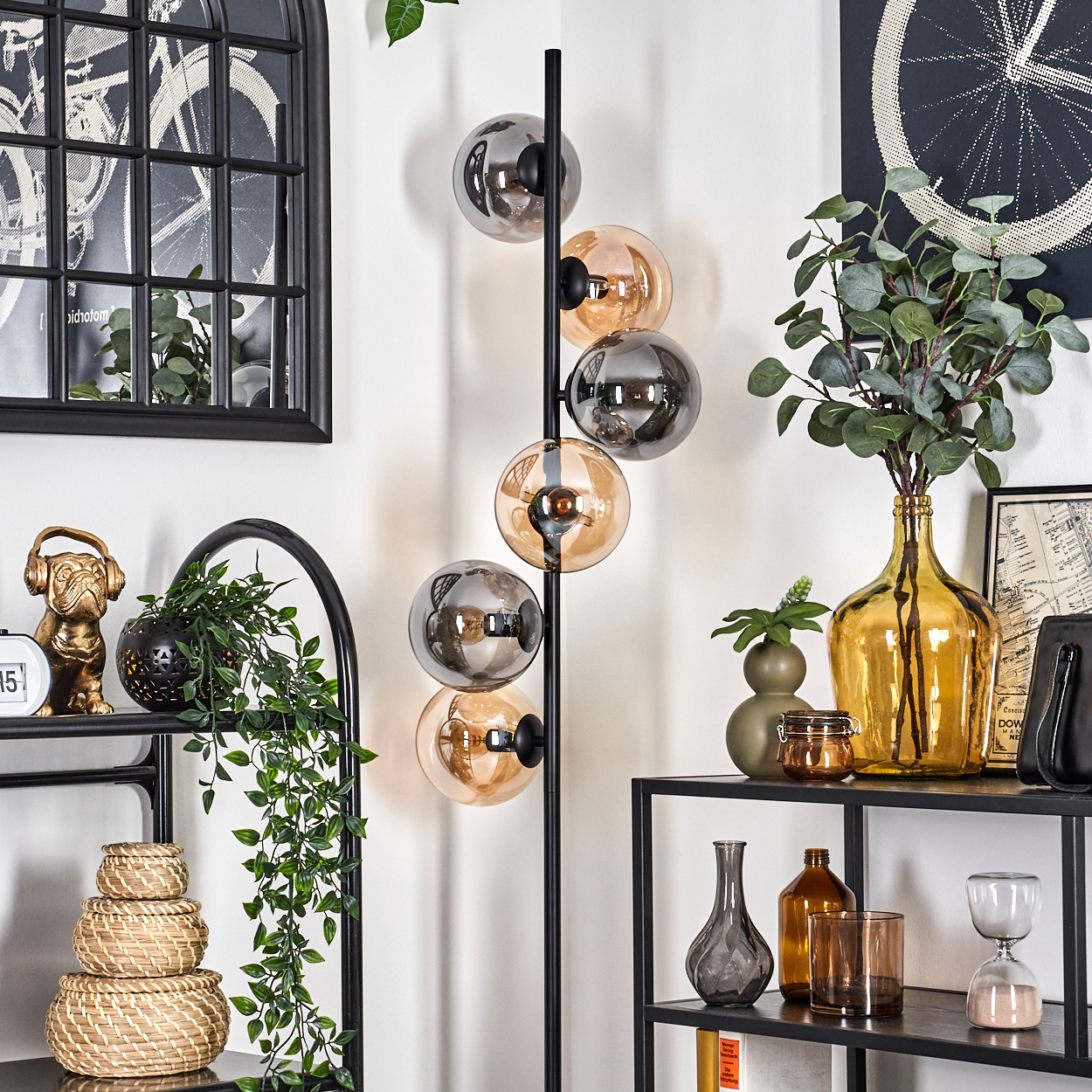 Eine schwarze Stehlampe mit Glasschirmen. Die Lampe befindet sich in einem Raum mit anderen Möbeln und Dekorationen.