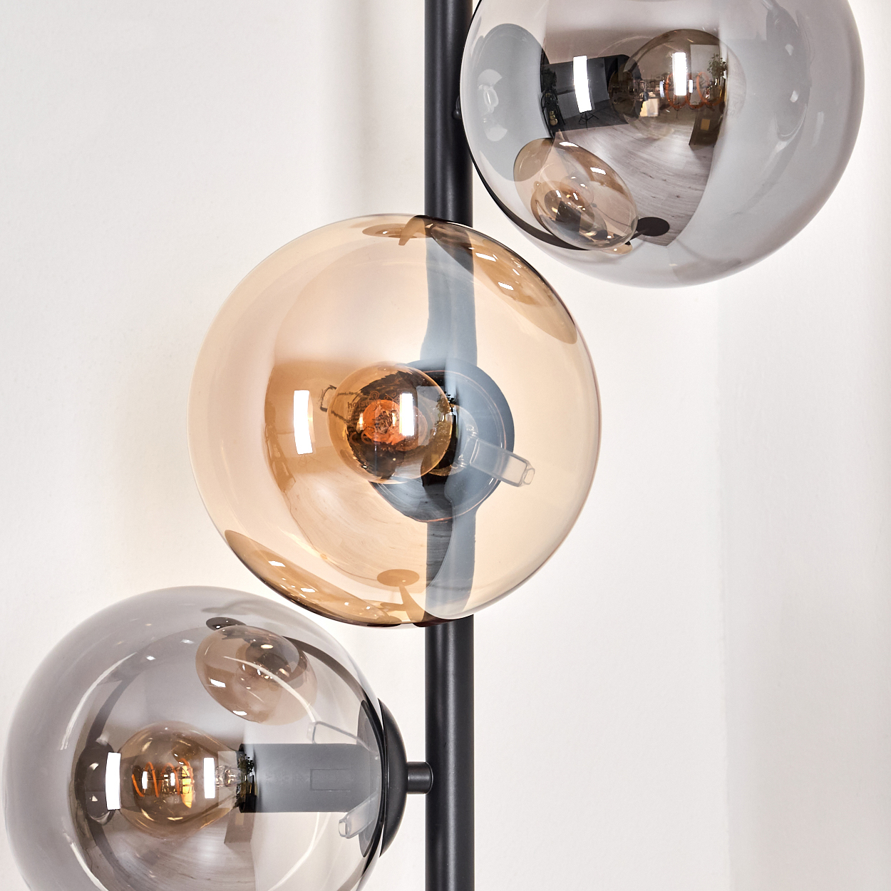 Nahaufnahme einer schwarzen Stehlampe mit mehreren Glasschirmen. Die Schirme sind bernsteinfarben und grau.