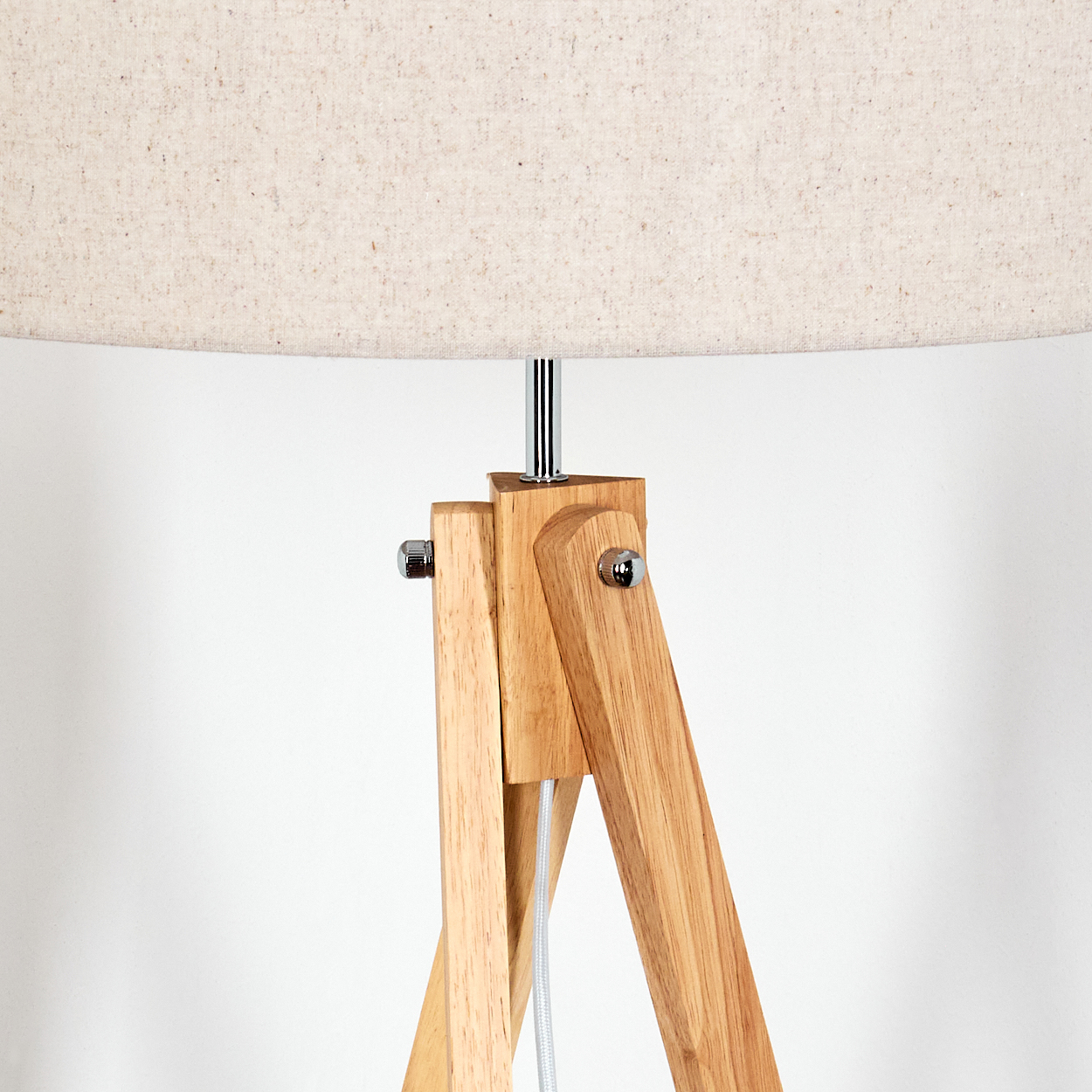 Nahaufnahme des Holzrahmens und des beigen Schirms einer Stehlampe mit Stativ.