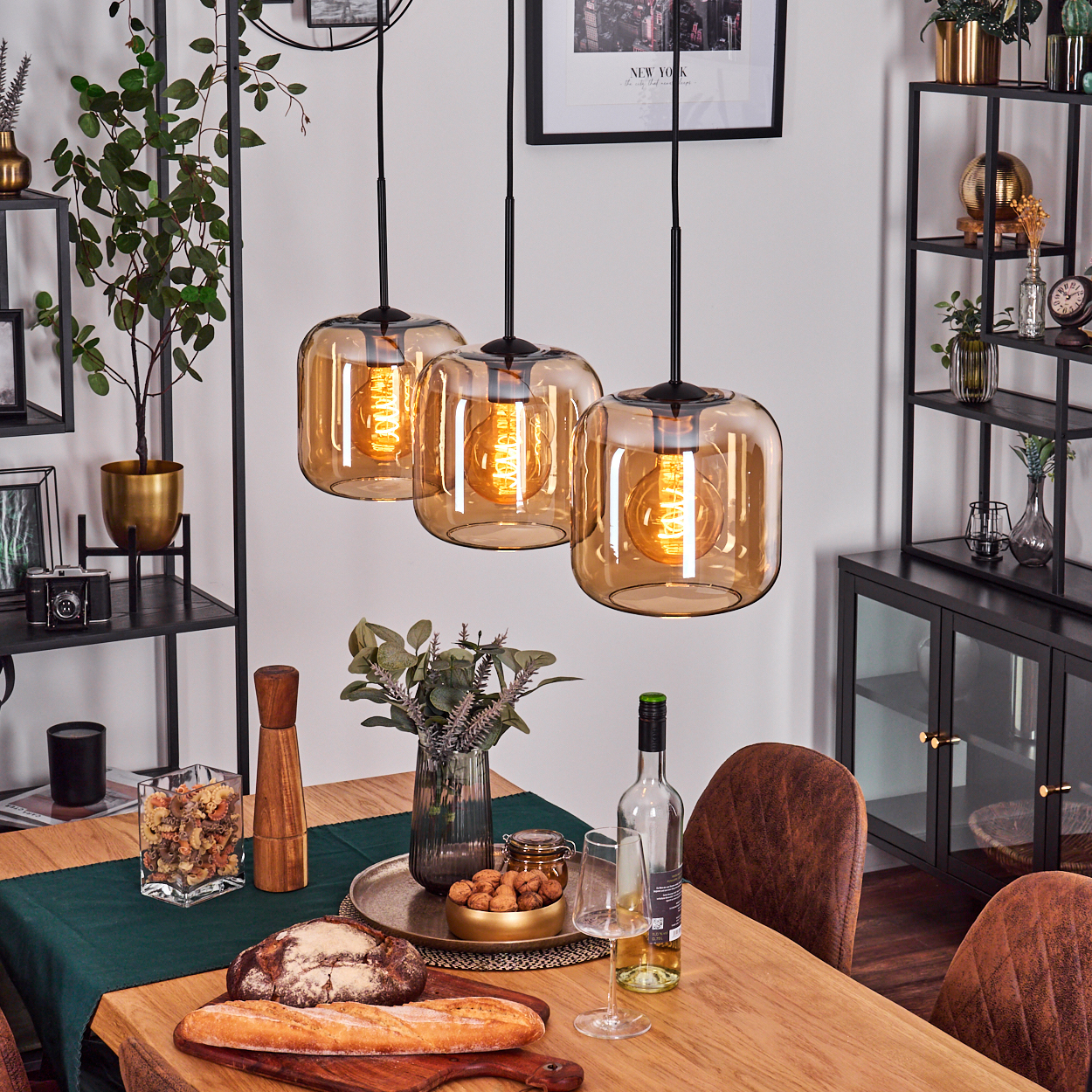 Esstisch mit drei Pendelleuchten darüber, Essen und Wein. Inneneinrichtung ist vorhanden.