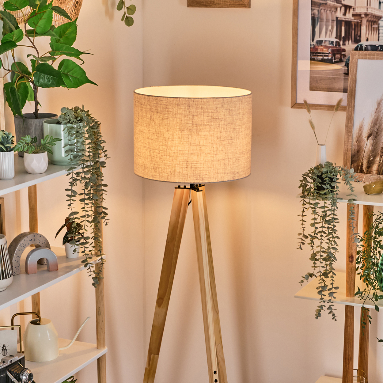 Holz-Stativ-Stehleuchte mit Leinen-Schirm. Andere Pflanzen und Dekorationen sind im Hintergrund zu sehen.