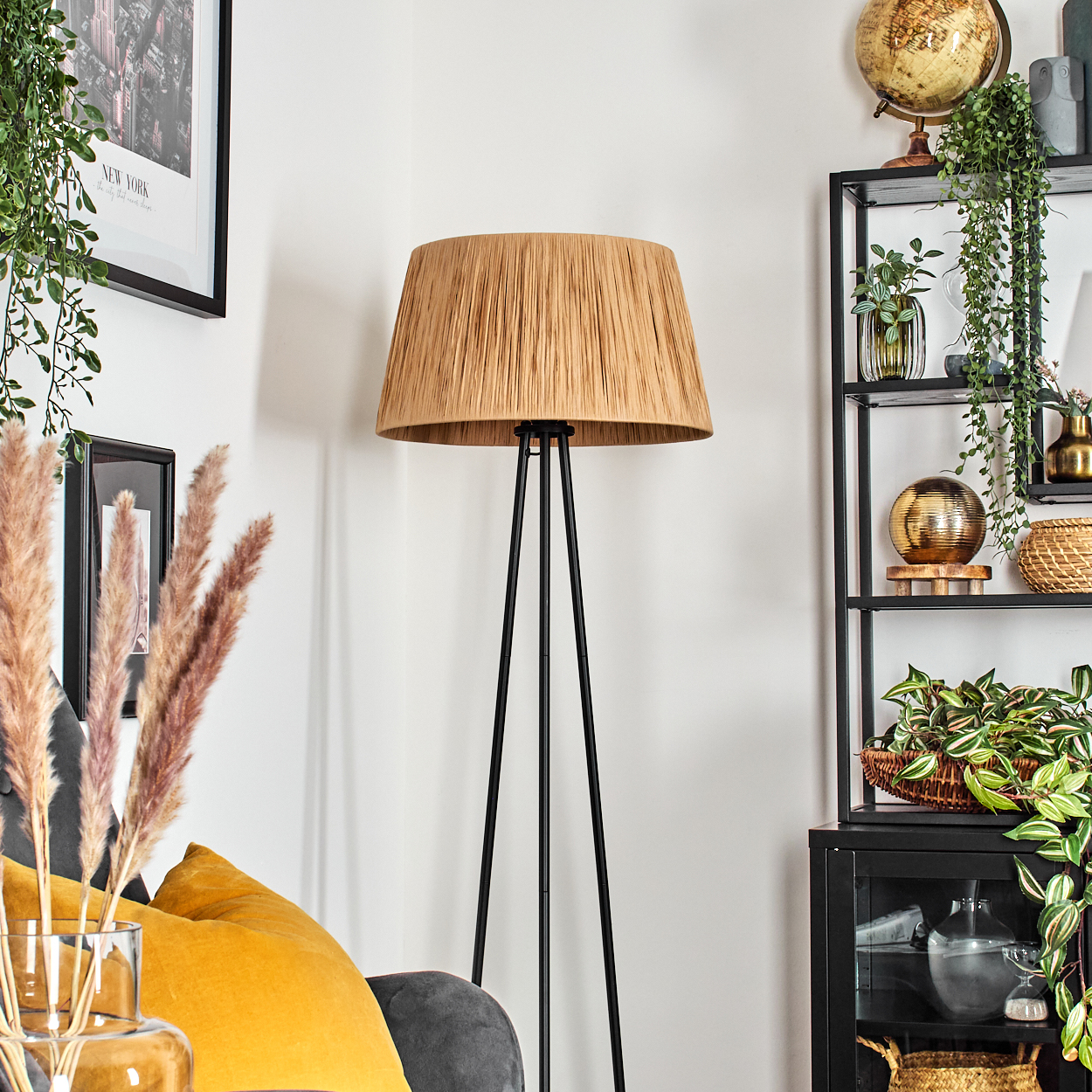 Stehlampe mit beigem Schirm, Sofa und Dekoration in einem Raum.
