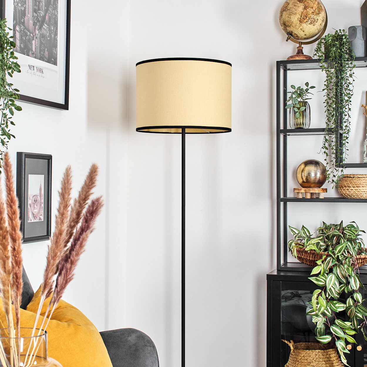 Stehlampe mit beigem Schirm, schwarzem Ständer und Wohnzimmer-Einrichtung.