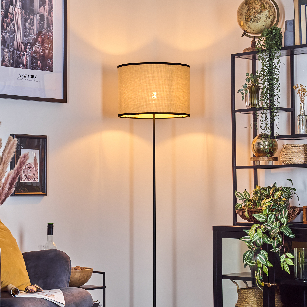 Beleuchtete Stehlampe mit beigem Schirm, in einem Wohnzimmer mit Dekoration und Beleuchtung.