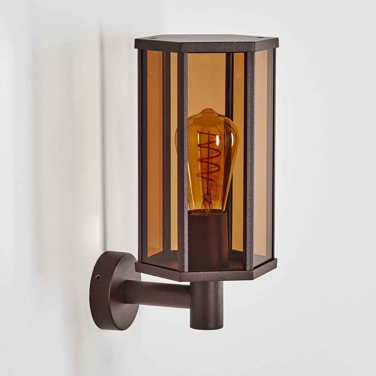 Braune Außenwandleuchte mit klarem Glas, einer Vintage-Edison-Glühbirne und an einer weißen Wand montiert.