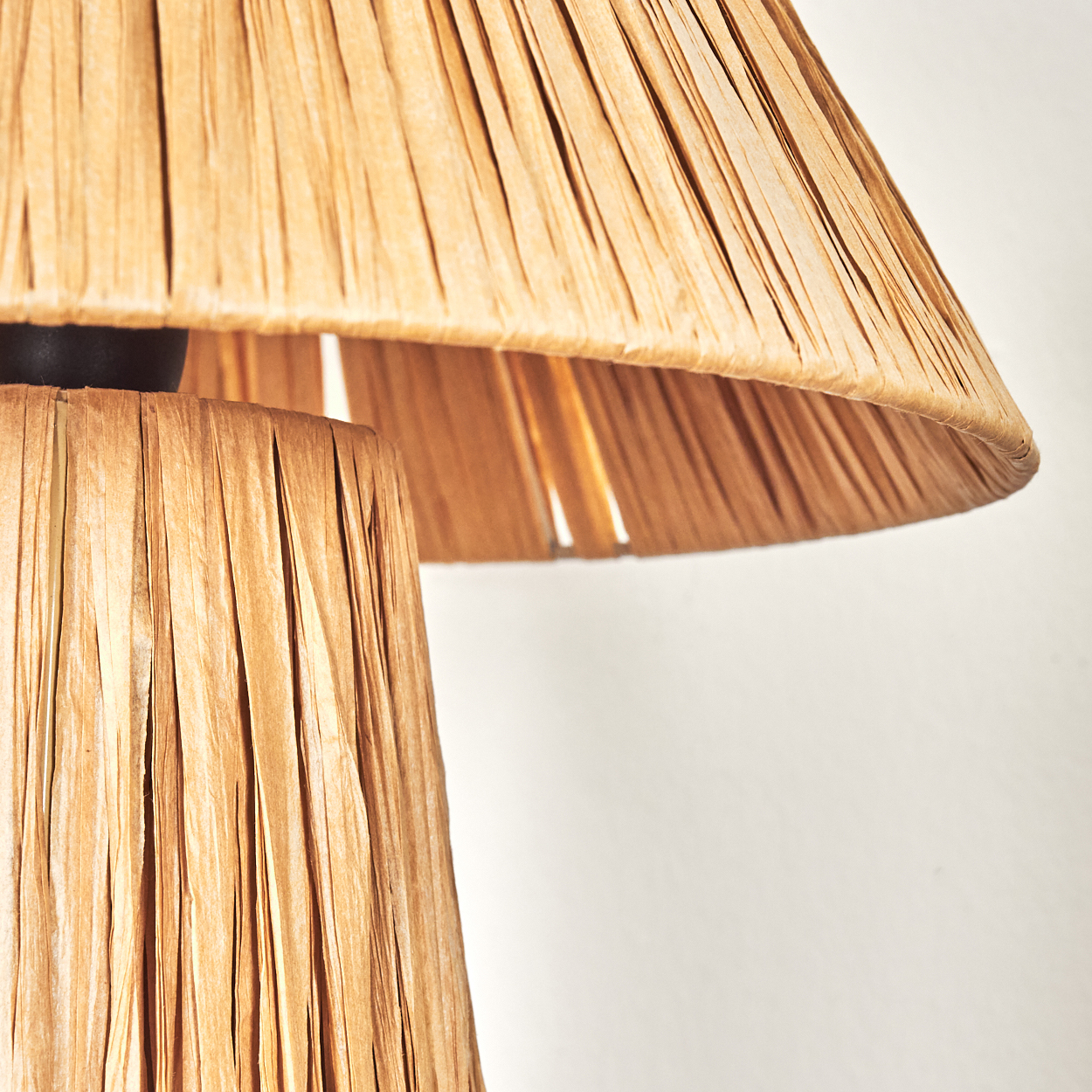Nahaufnahme einer Lampe. Der Schirm ist beige mit vertikalen Linien. Der Sockel ist schwarz.