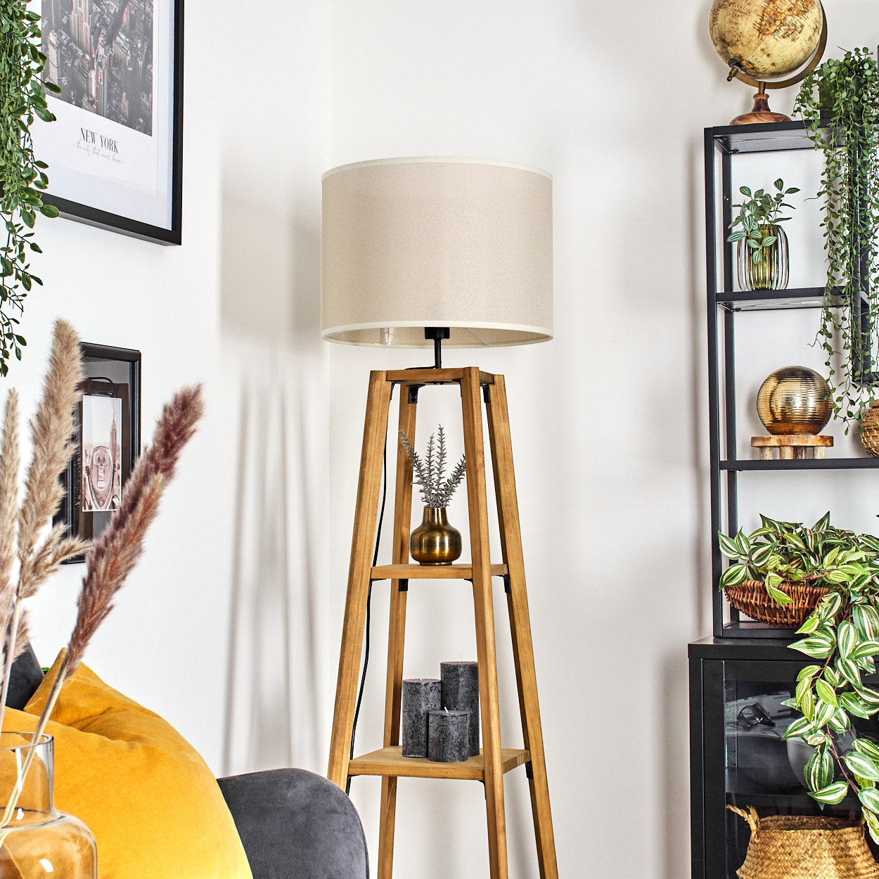 Stehlampe aus Holz, beiger Schirm, Holzrahmen, Vase, Kerzen. Innenraum mit Pflanzen und Dekorationen.