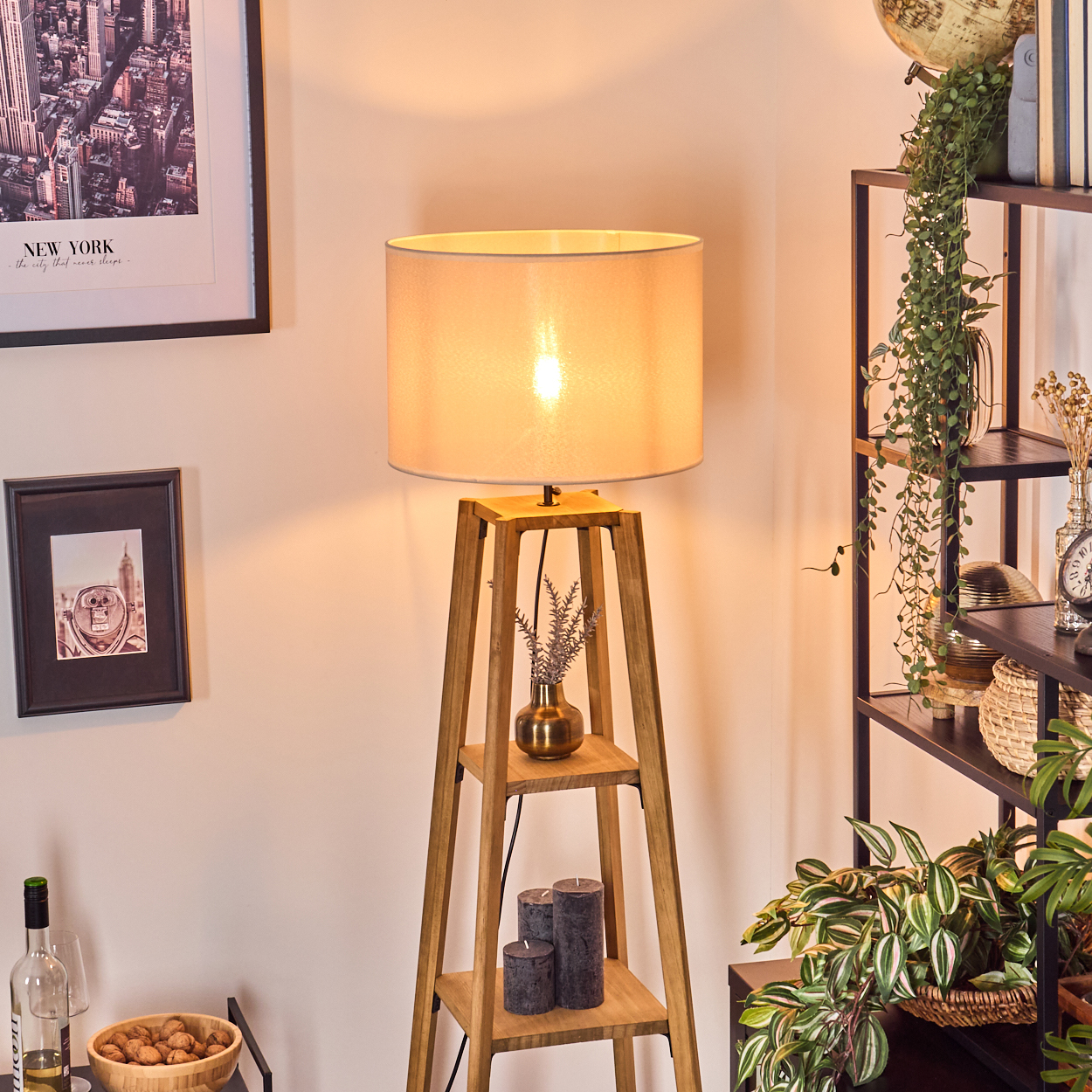 Holz-Stehlampe mit beigefarbenem Lampenschirm, Holzregalen und Kerzen. Hintergrund: New York Bild.