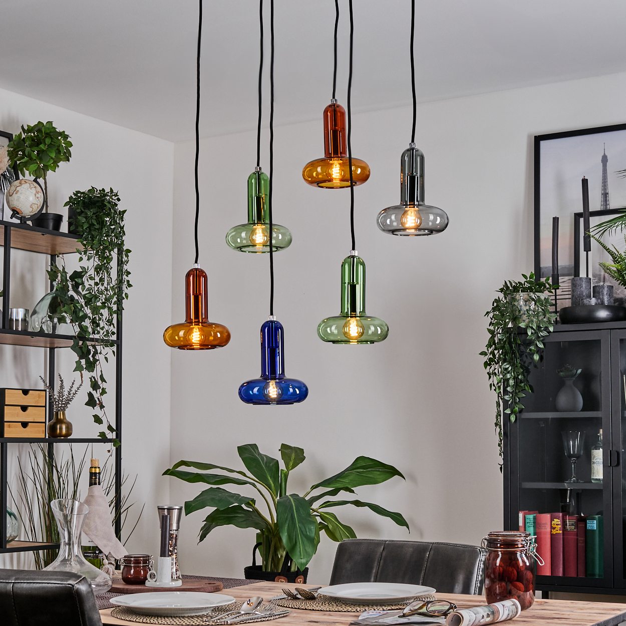 Sechs bunte Glas-Pendelleuchten über einem Esstisch.