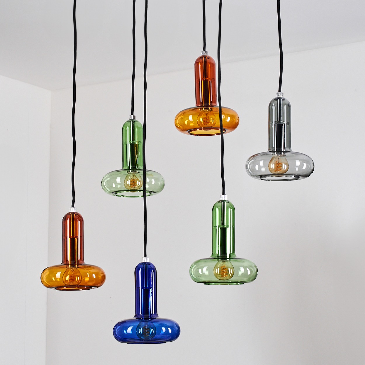 Draufsicht auf Hängeleuchten. Sechs bunte Glasschirme mit sichtbaren Glühbirnen.