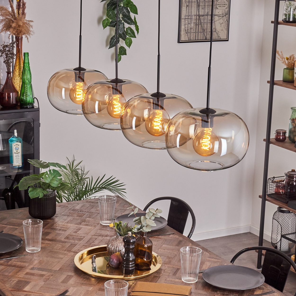 Esszimmer mit Pendelleuchten über einem Holztisch. Die Leuchten haben bernsteinfarbene Glaskugeln.