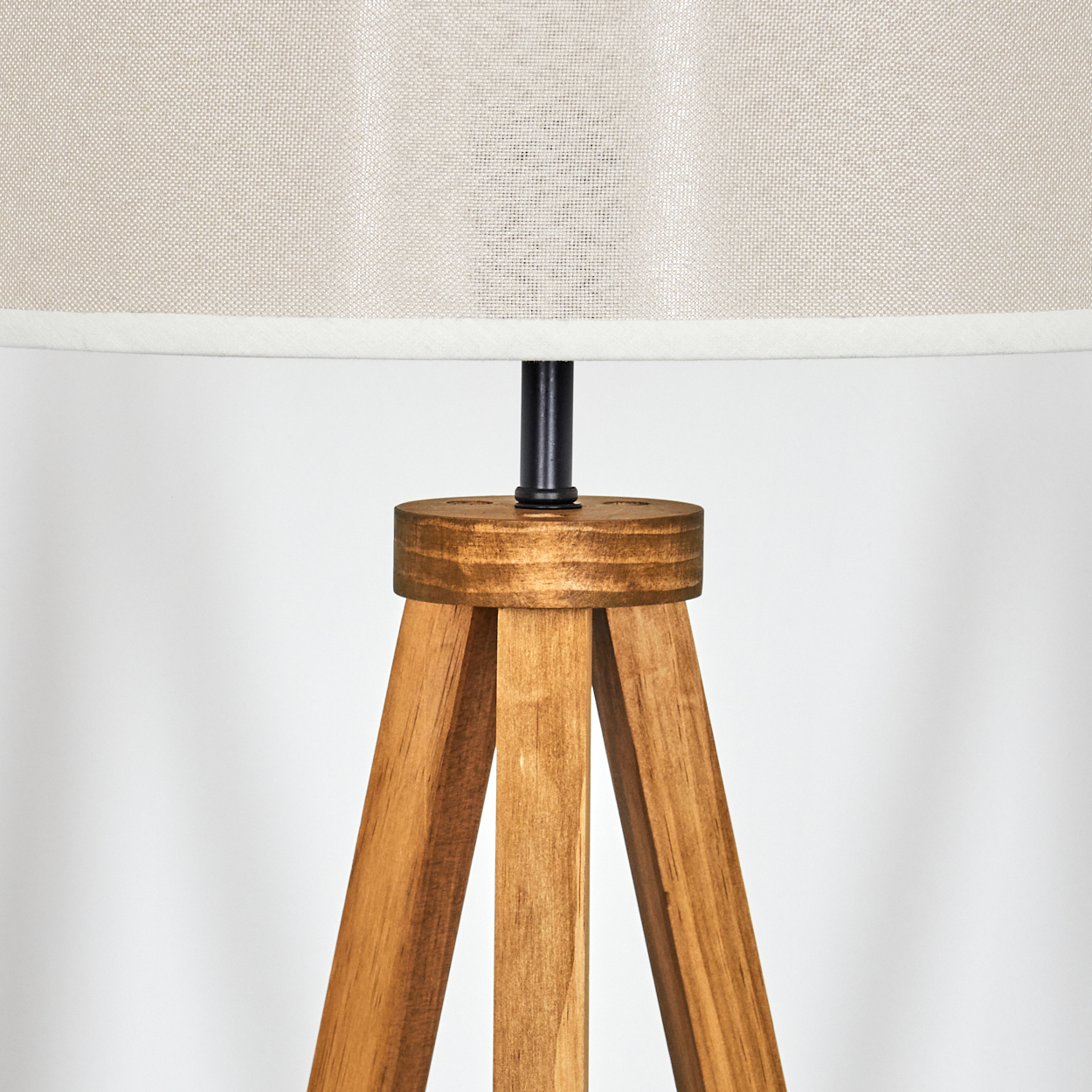 Nahaufnahme eines Holzlampenfußes mit cremefarbenem Schirm. Die Lampe ist ausgeschaltet.