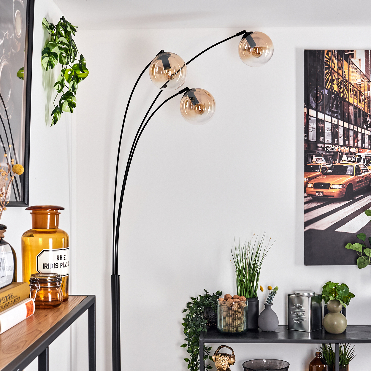 Stehlampe mit gebogenen schwarzen Armen und Glaskugelleuchten. Hintergrund mit Deko.