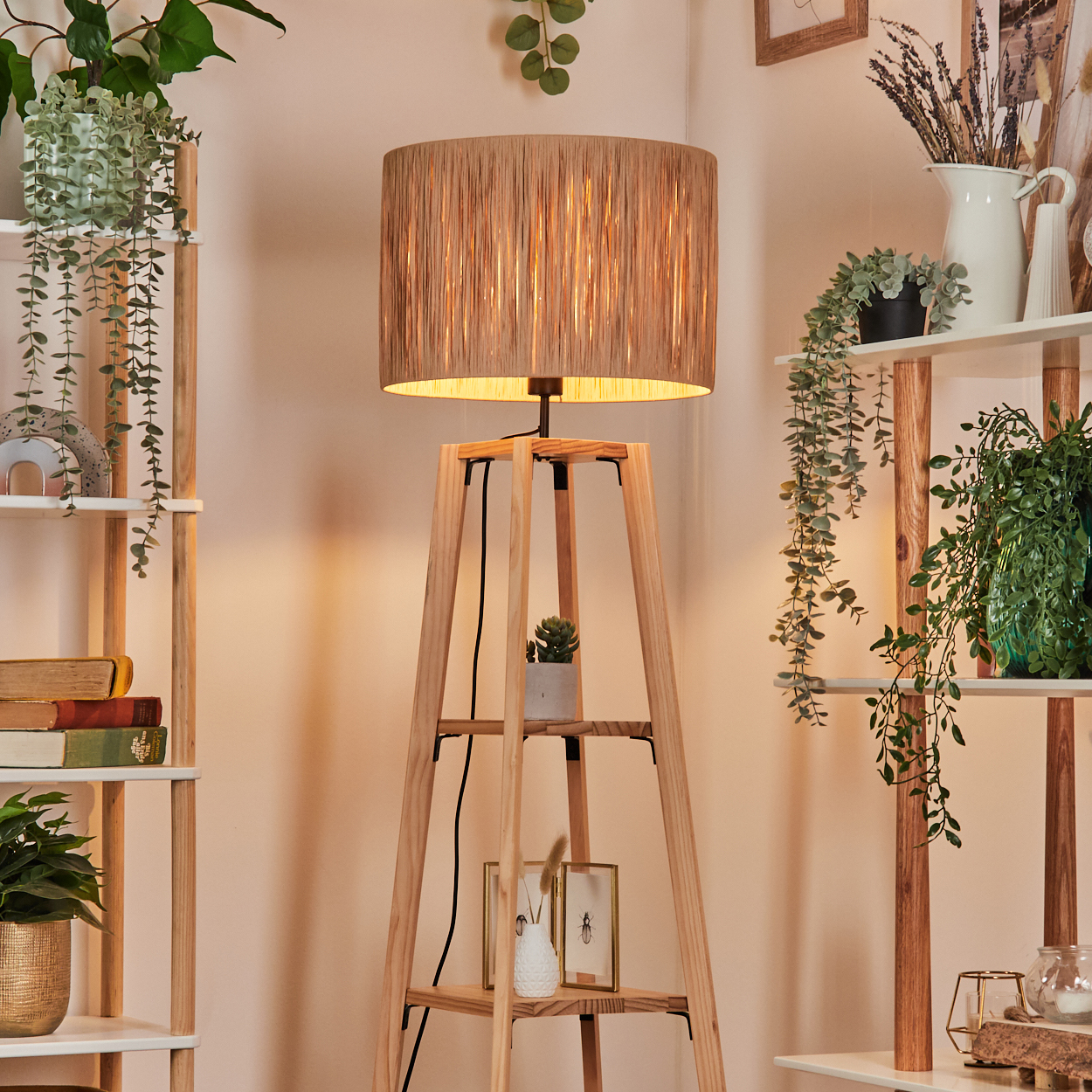Eine Holz-Stehlampe mit beigem Lampenschirm, umgeben von Regalen mit Pflanzen.