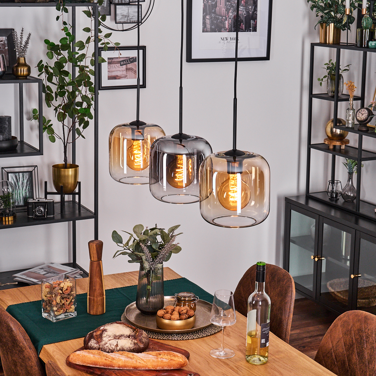 Esszimmer mit Holztisch, hängenden Glasleuchten und Dekoration. Weiße Wand, grüner Tischläufer.