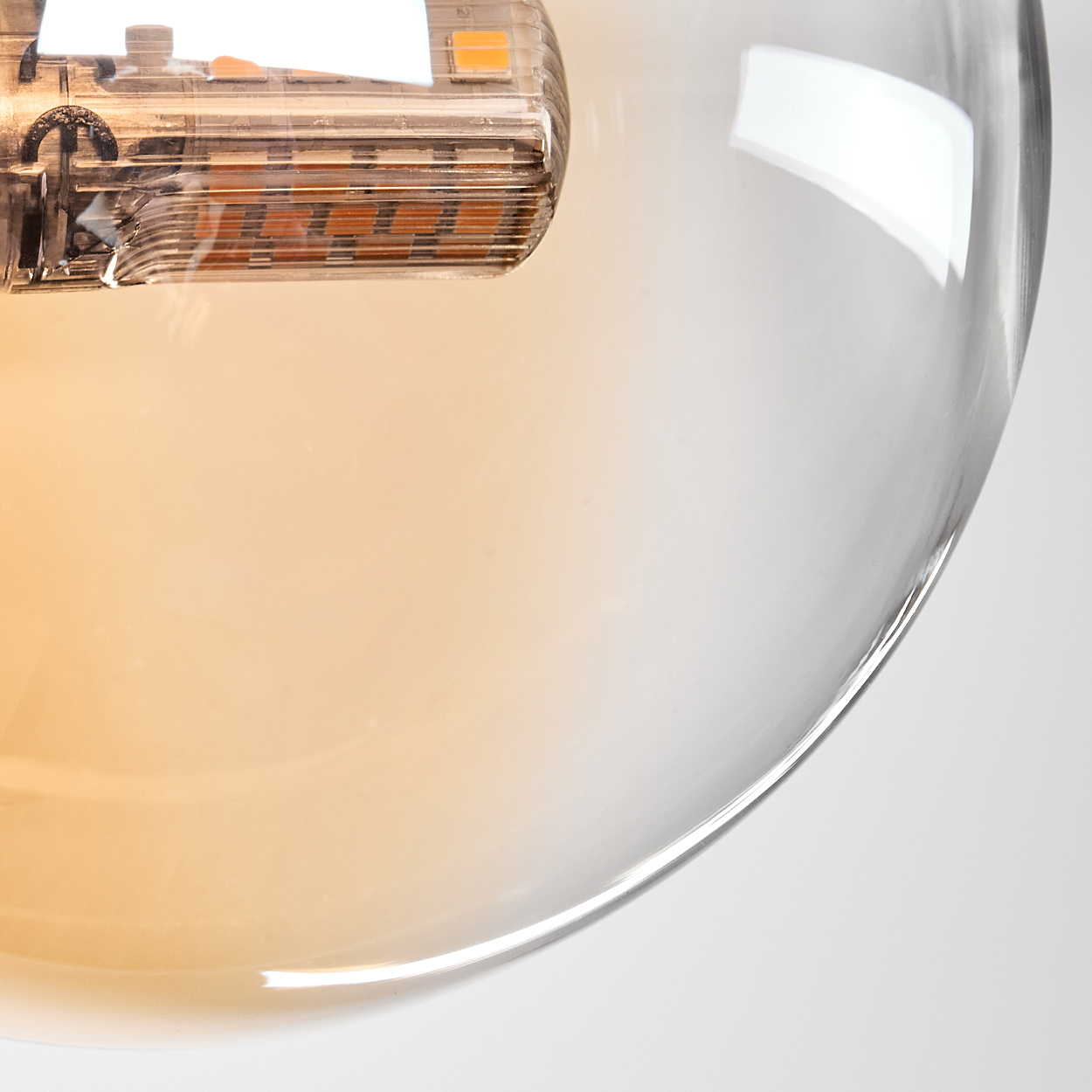 Nahaufnahme einer Glas-Pendelleuchte mit sichtbarer Glühbirne, zeigt detaillierten Glühfaden.