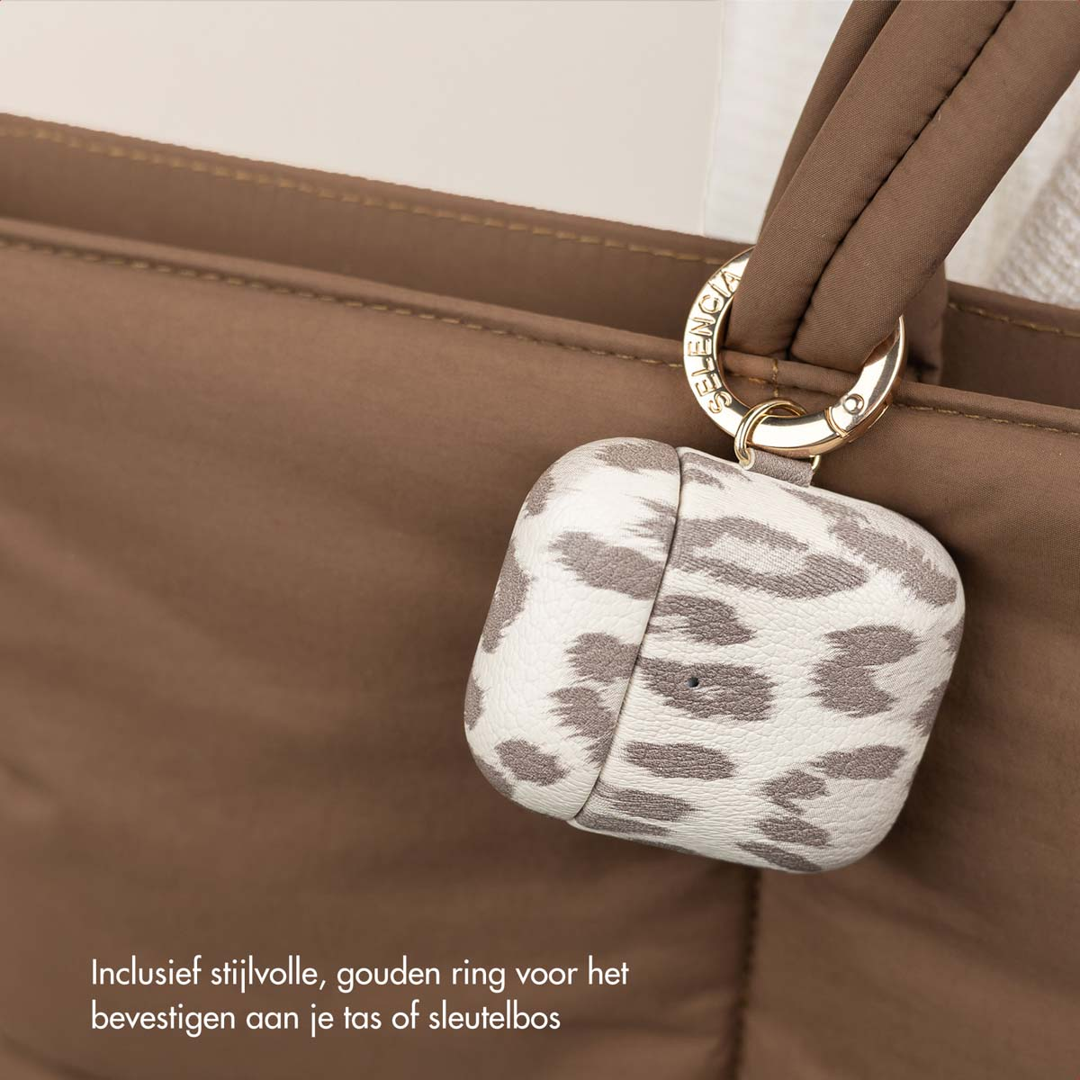 Custodia AirPods con stampa leopardata attaccata al manico di una borsa tote marrone.