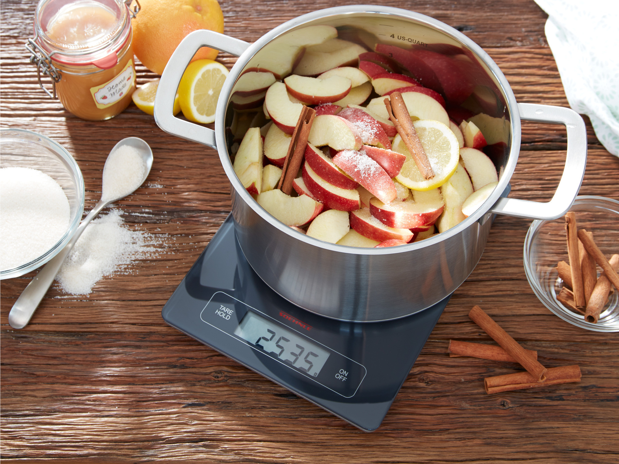 Waga kuchenna z garnkiem plastrów jabłka. Składniki i drewniana powierzchnia są widoczne.