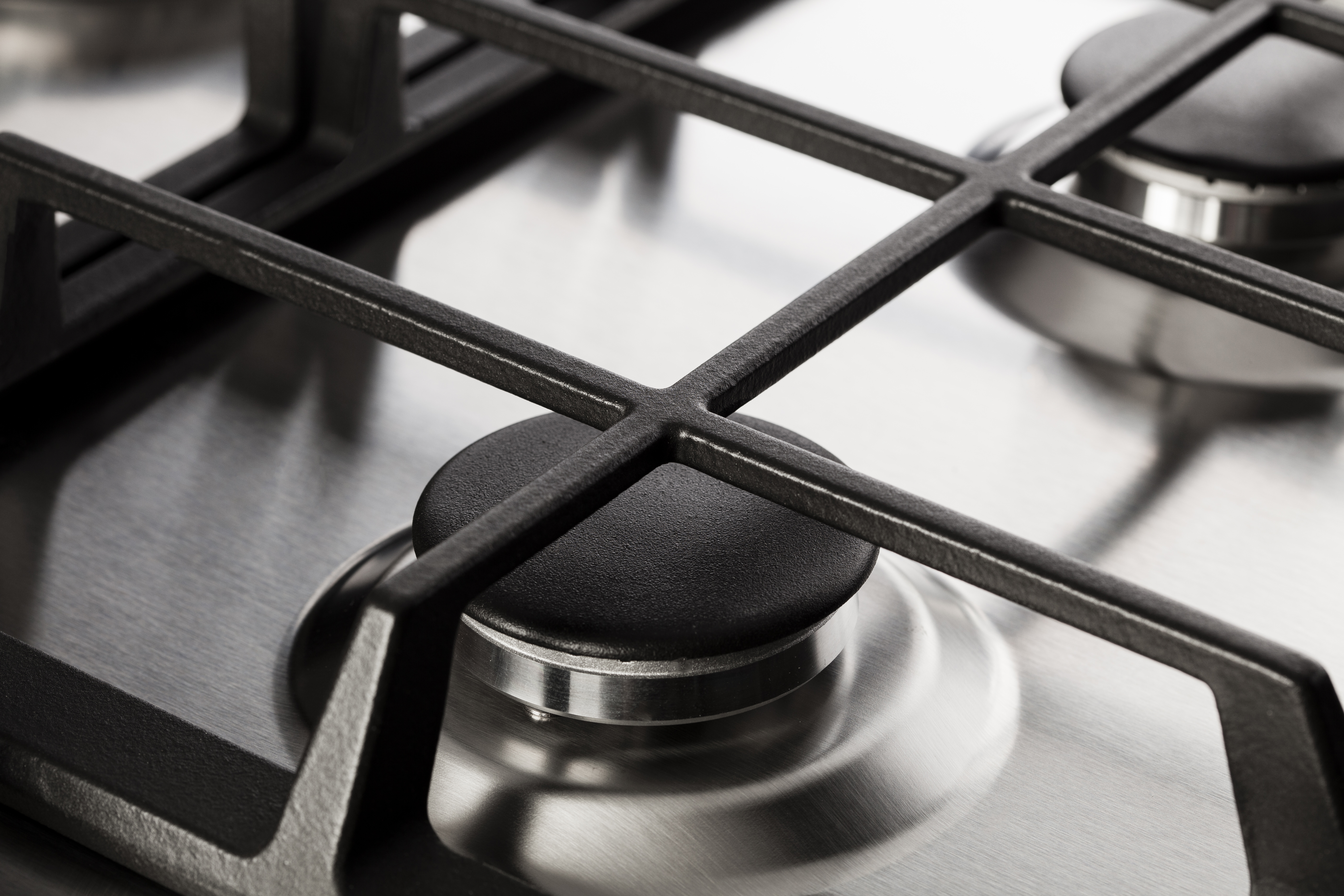 Primo piano della griglia del piano cottura a gas. Griglia nera su una superficie in acciaio inox. PremierTech.