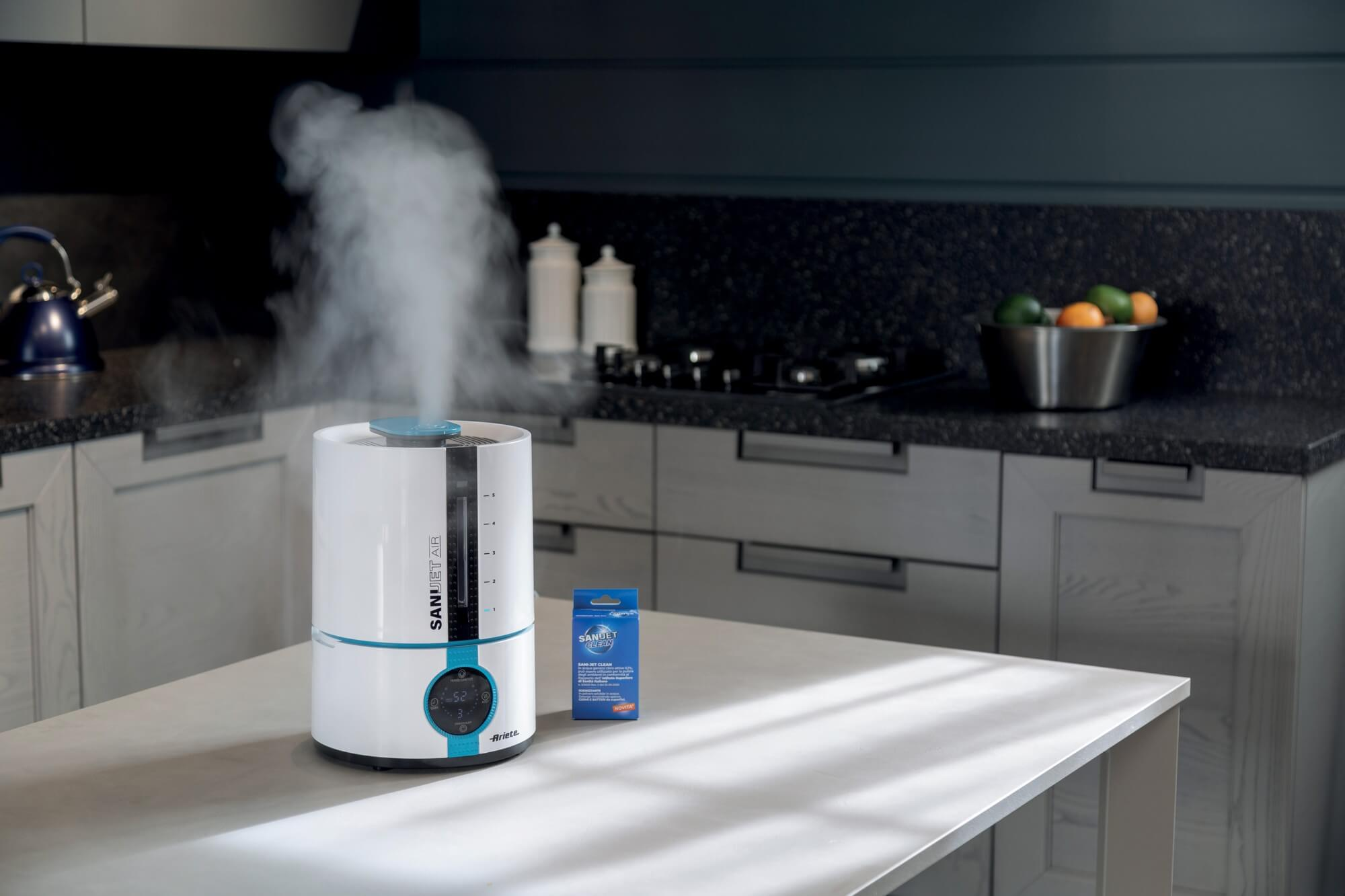 Un umidificatore bianco e blu con vapore, su un ripiano bianco in cucina.