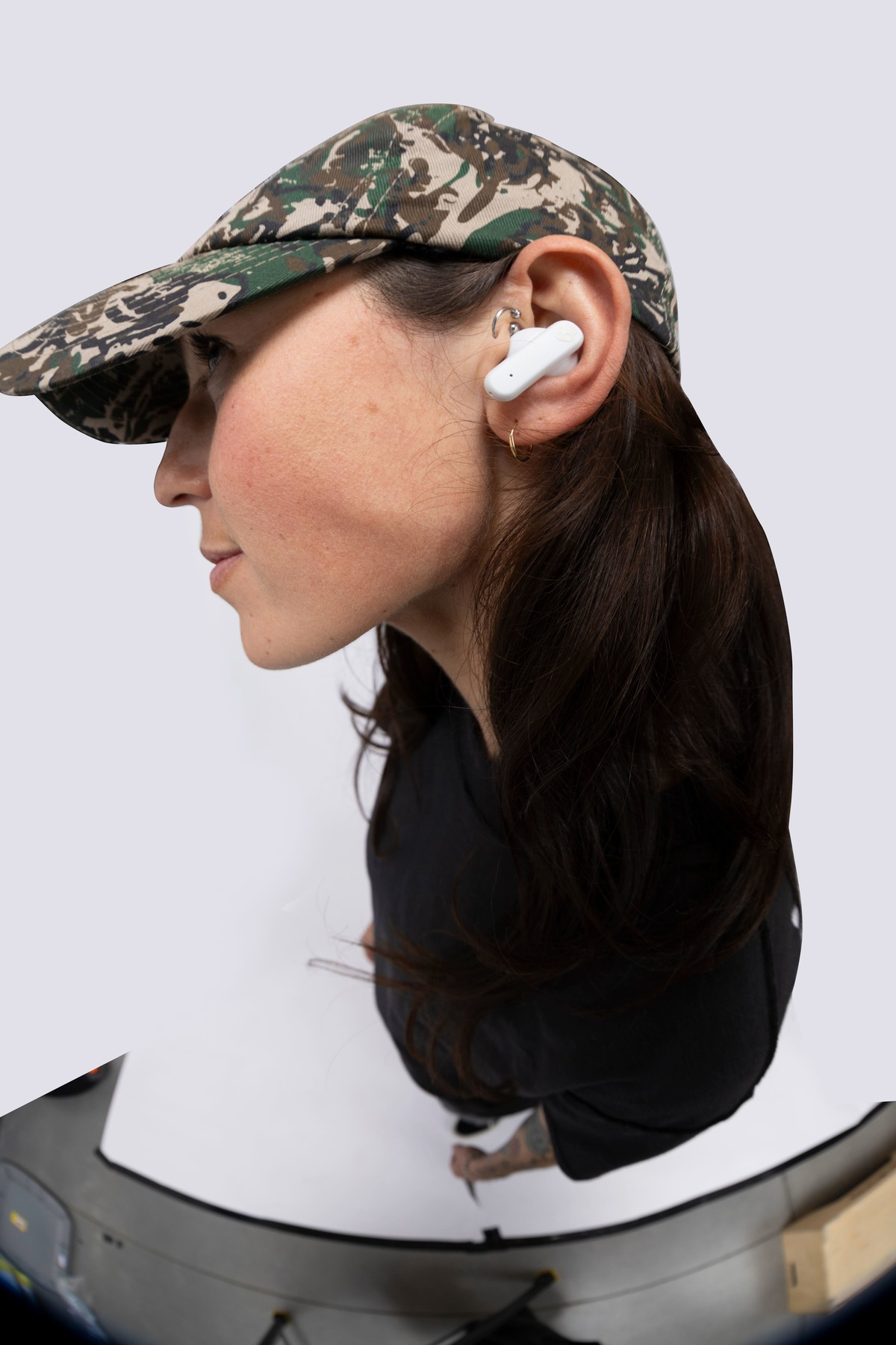 Kobieta w słuchawkach i czapce moro. Białe tło.