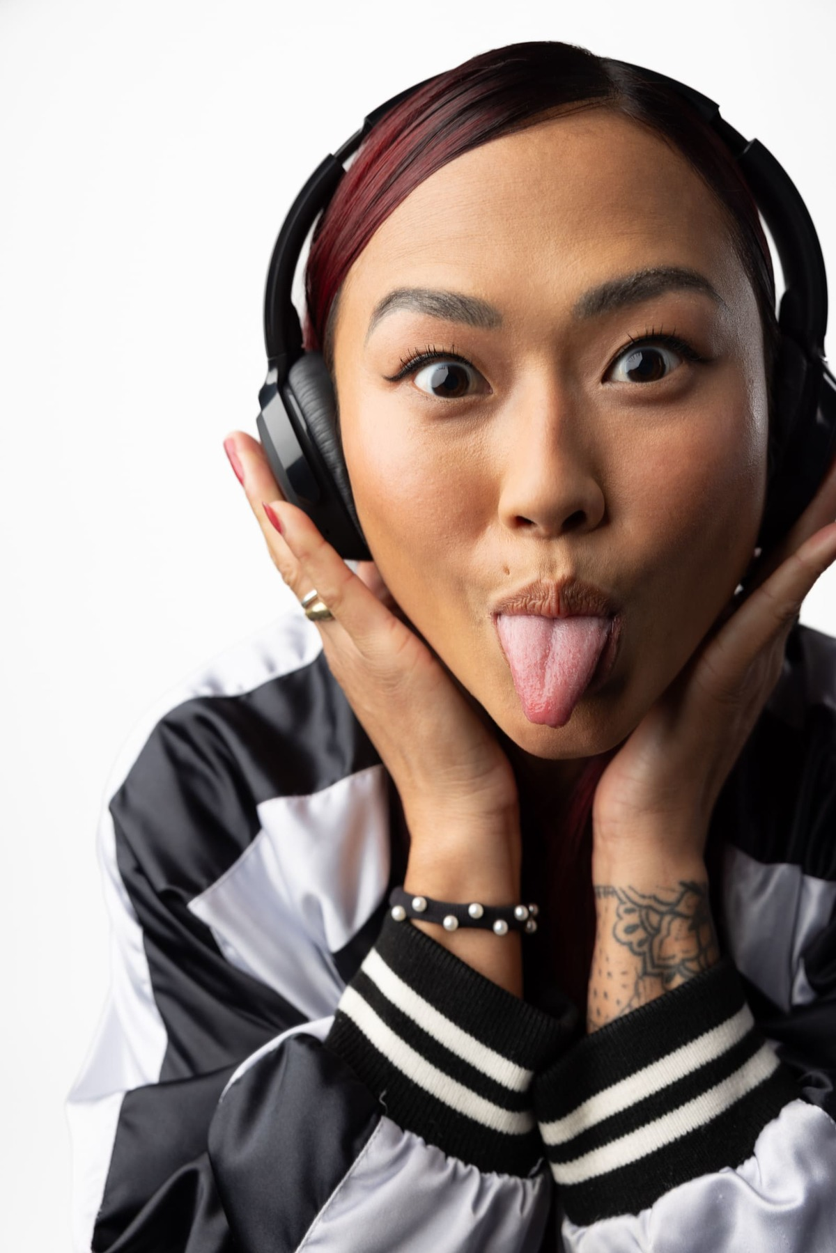 Kobieta z rudymi włosami, robiąca minę, ma na sobie słuchawki i kurtkę.