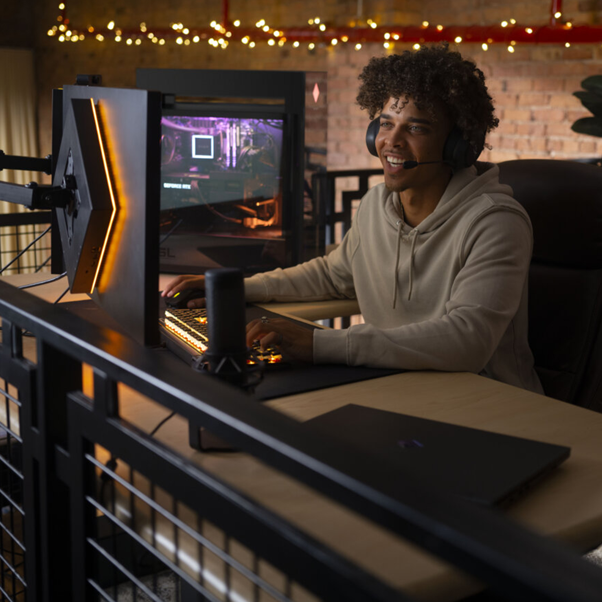 Uśmiechnięty mężczyzna grający w słuchawkach i podświetlaną klawiaturą w ciemnym pokoju.