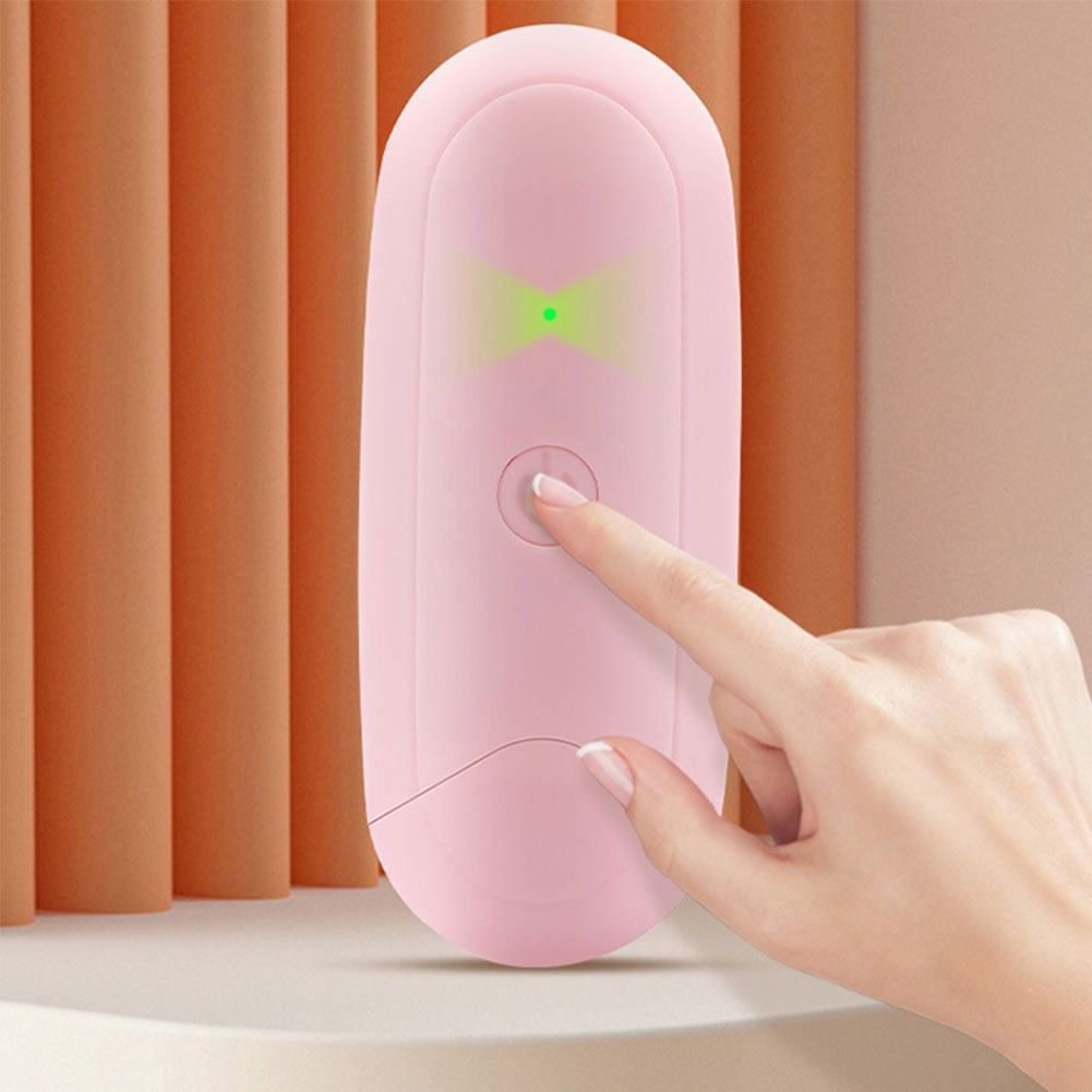 Hand berührt den Einschaltknopf eines rosa Geräts. Brauner Hintergrund. Grünes Licht sichtbar.