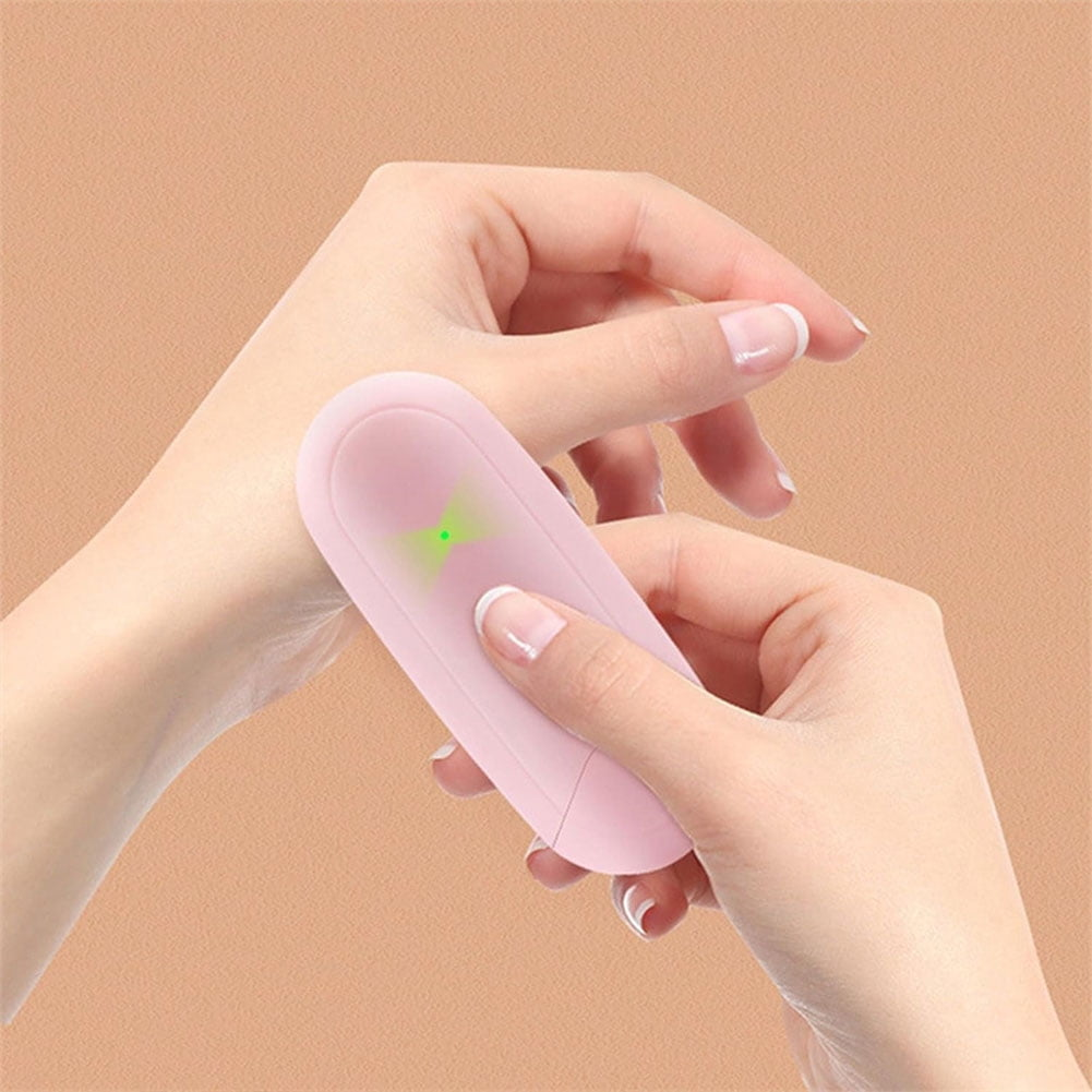 Eine Hand benutzt rosa Gerät auf Haut. Brauner Hintergrund. Grünes Licht sichtbar.