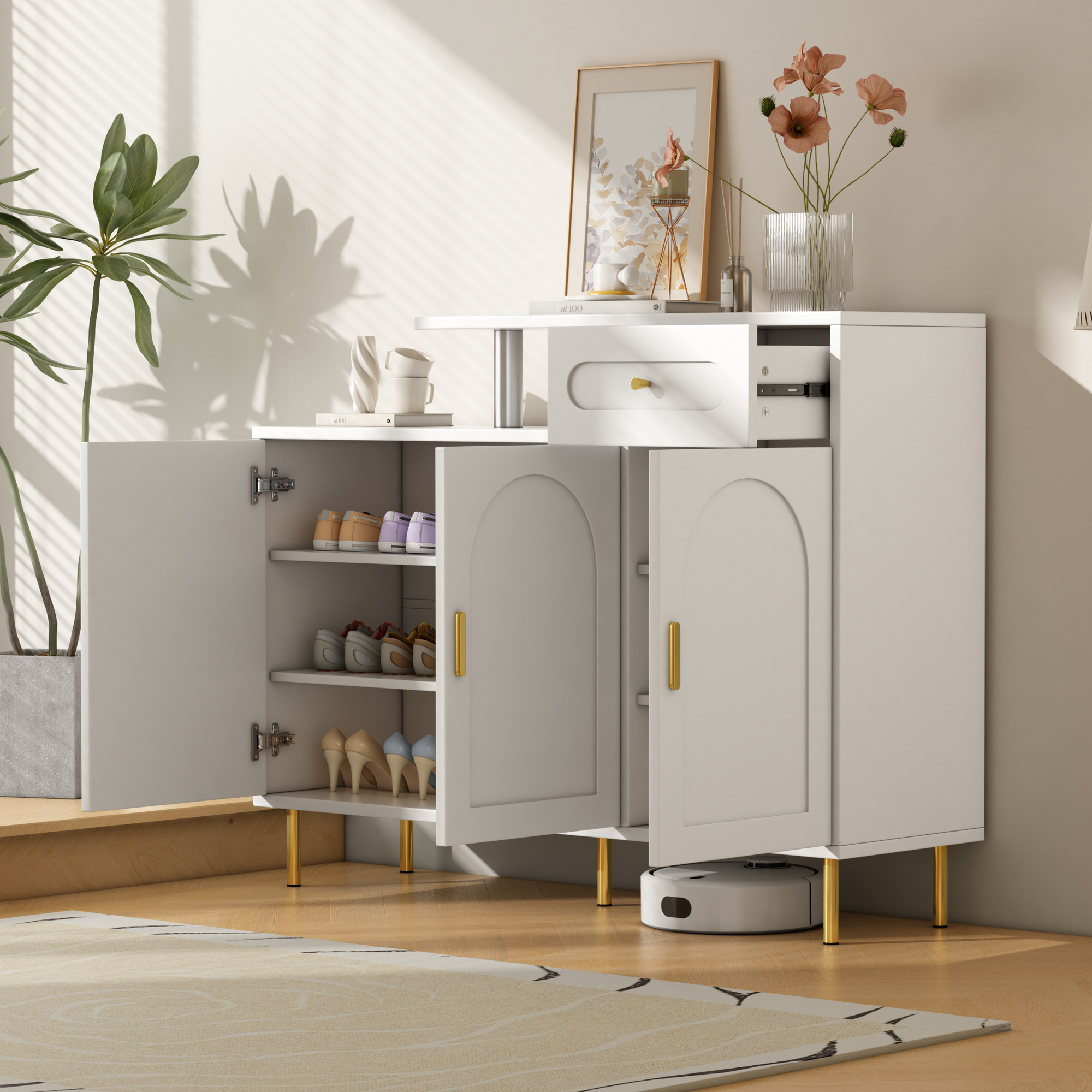 Weißer Schrank mit offenen Türen, Schuhen, goldenen Beinen und Griffen. Blumen und Bild oben.