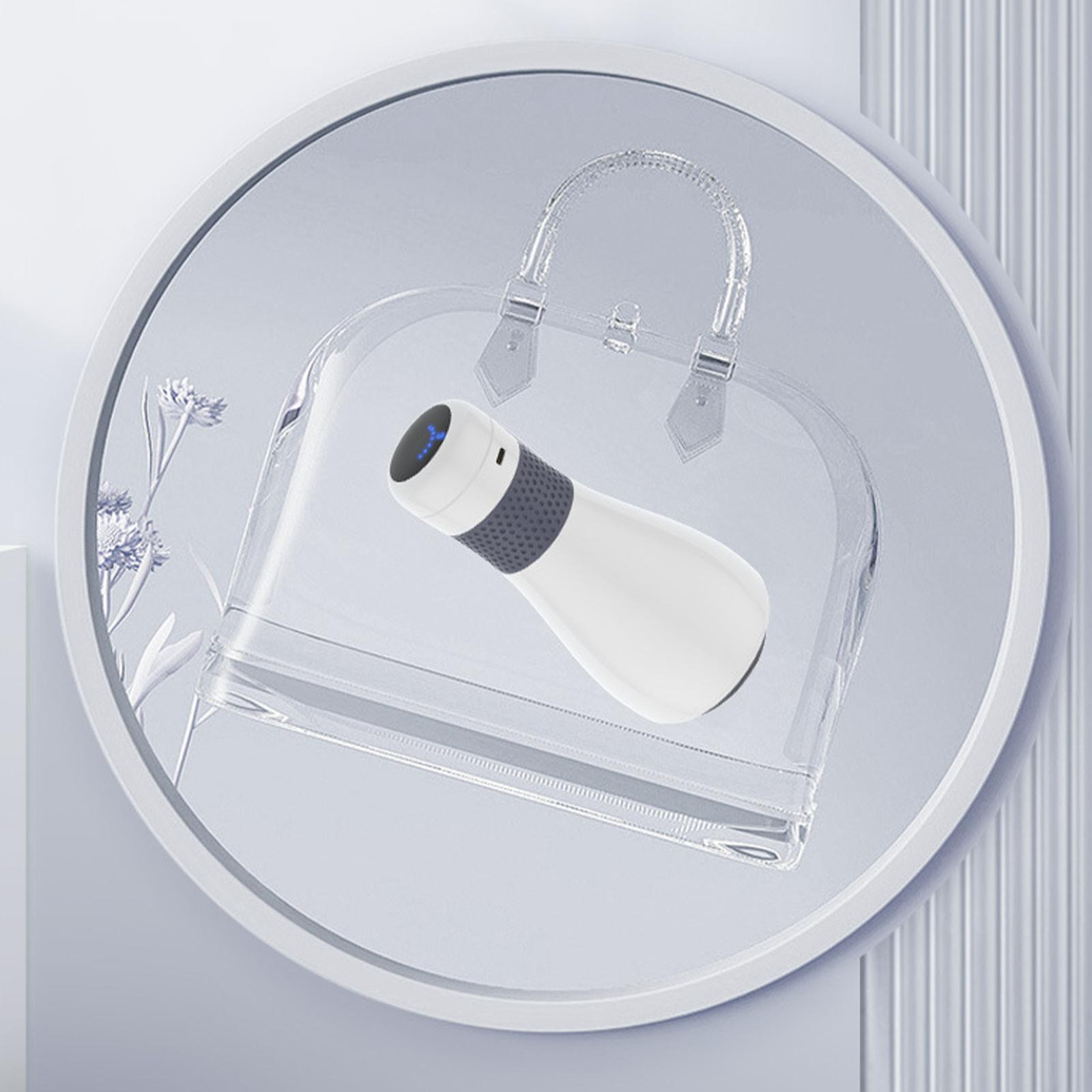 Weißes und graues Massagegerät in einer transparenten Handtasche auf hellem Hintergrund.