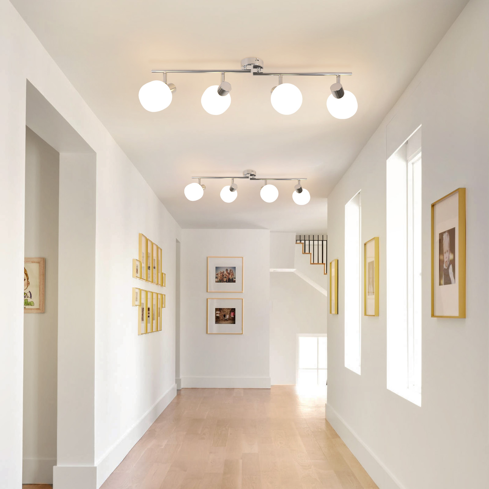 Un lungo corridoio con pareti bianche, pavimenti in legno e luci a soffitto. Ci sono quadri alle pareti.