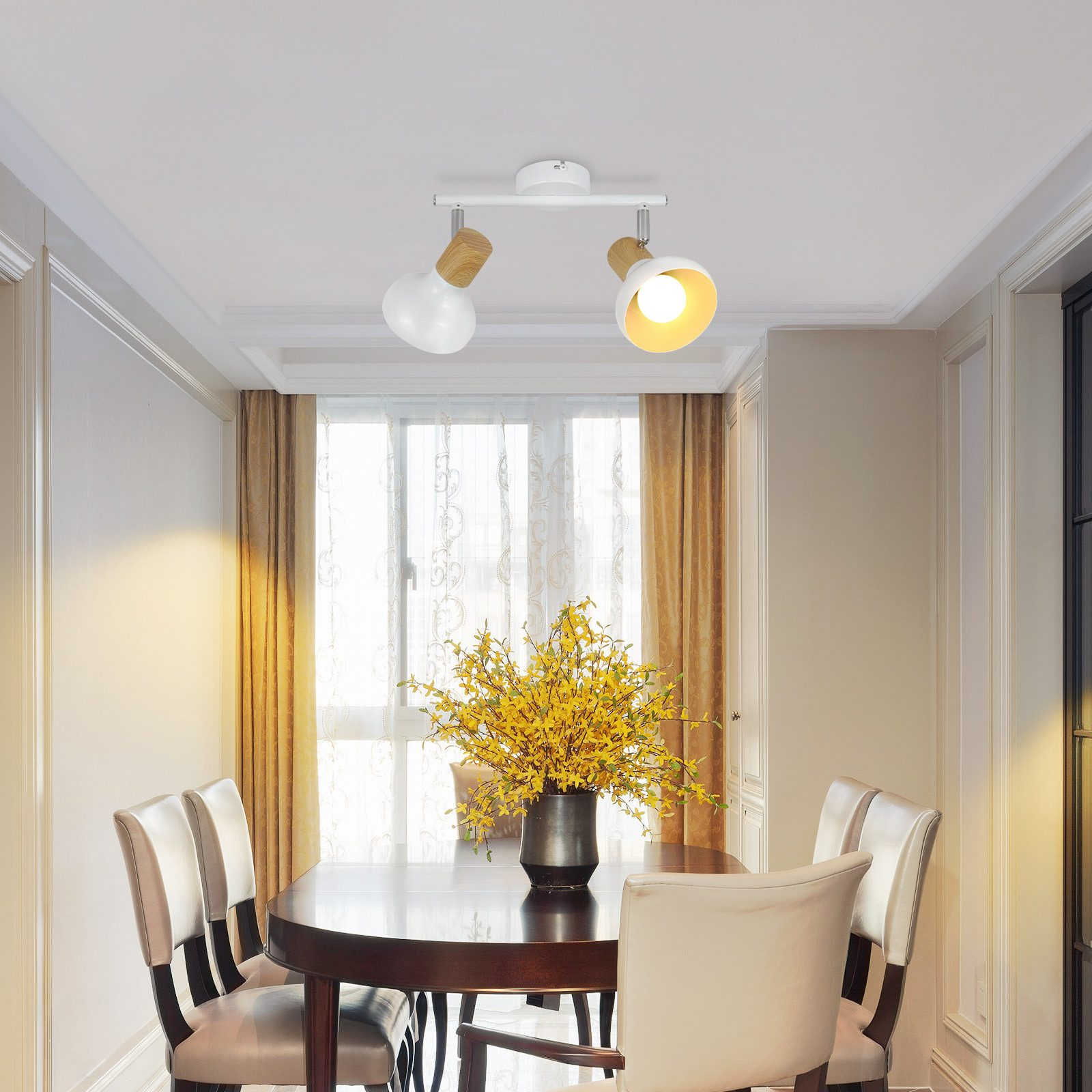 Sala da pranzo con soffitto bianco, tavolo rotondo, sedie e lampadario con due luci.