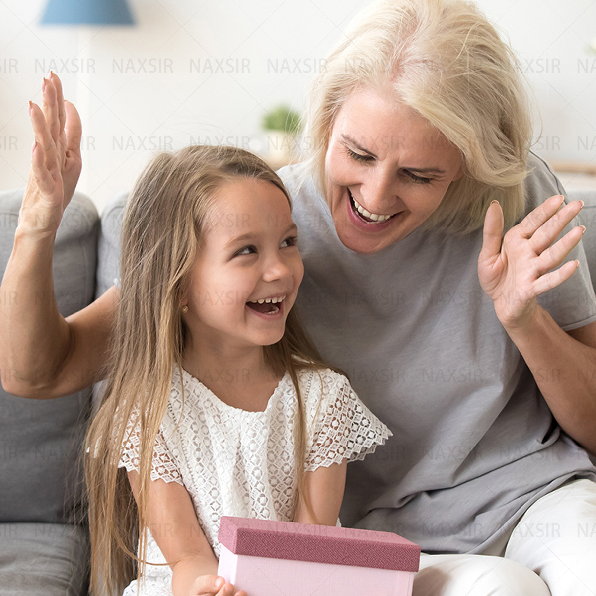 Una nonna e una nipote sorridono, guardando un pacco regalo.