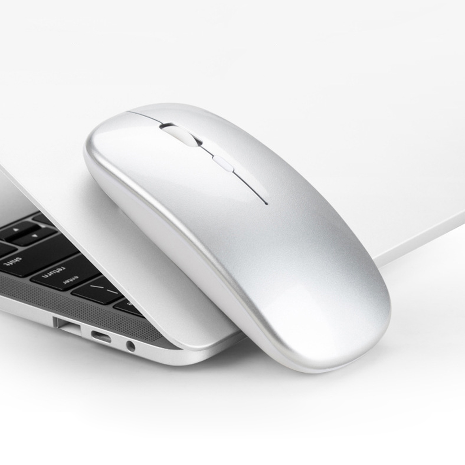 Mouse wireless argento su una tastiera di un laptop. Il mouse è sopra la tastiera.